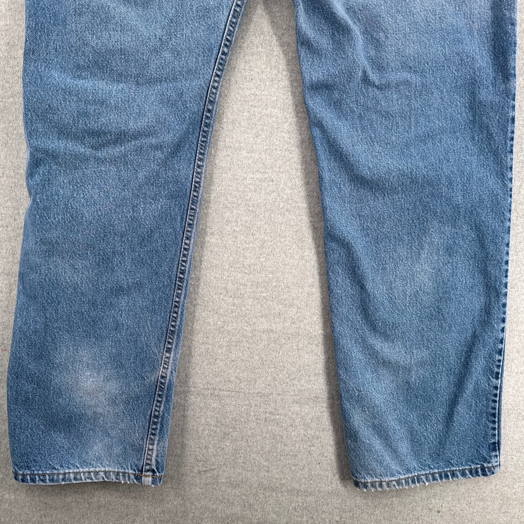 Pair of blue jeans on a beige surface. bottom of jeans