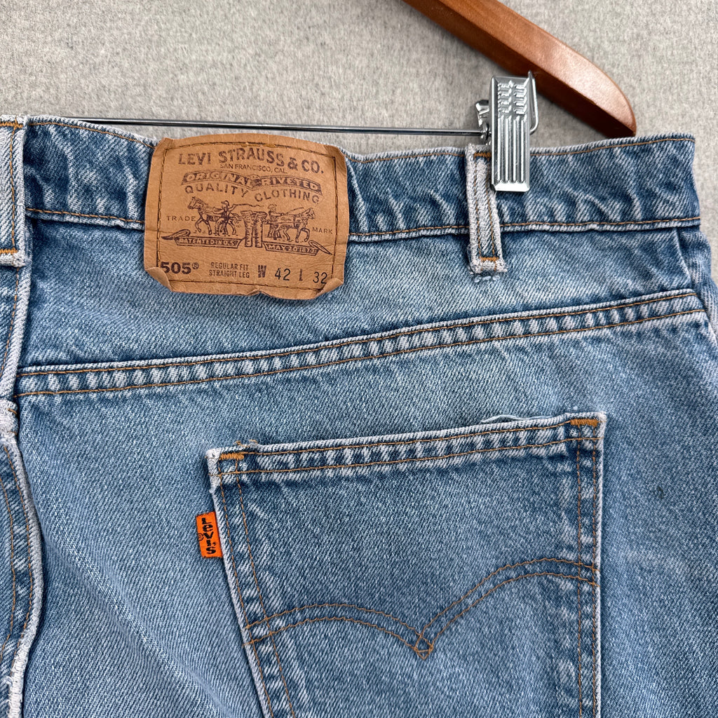 Close-up of Levi's jeans with brand label and hanger on a neutral background. Orange tab 505