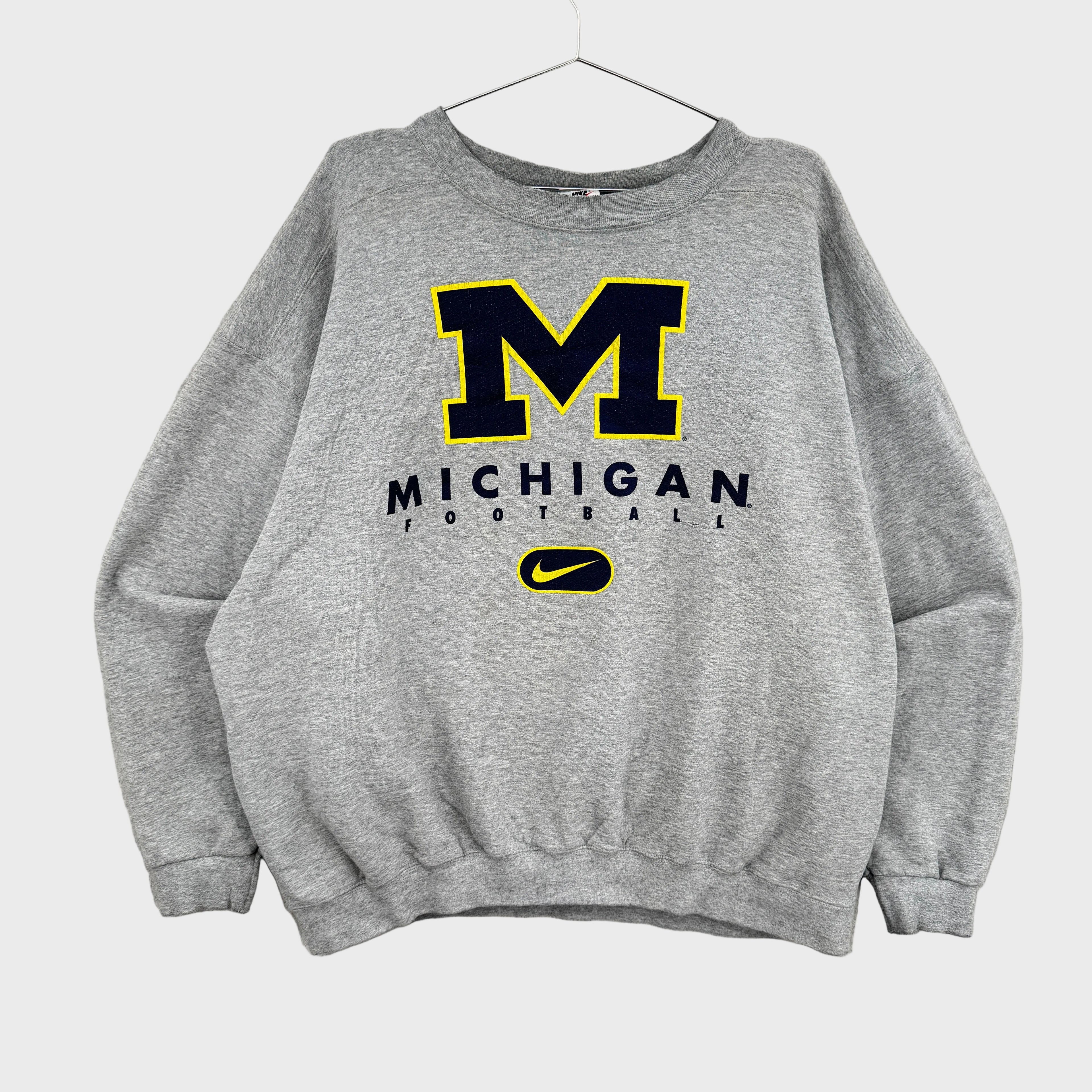 Gray sweatshirt with Michigan football logo on a gray background, Nike swoosh