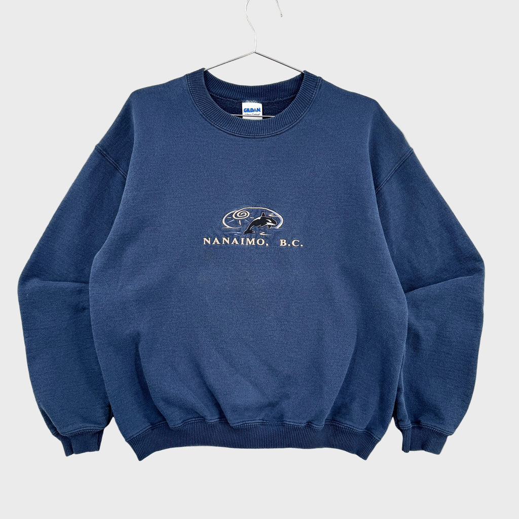 Blue sweatshirt with 'Nanaimo, B.C.' text and logo on a gray background. British Columbia souvenir with Orca Killer Whale