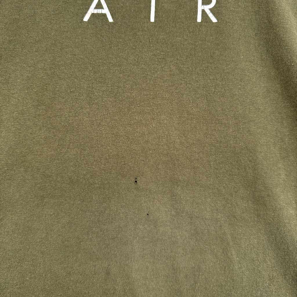 Close-up of a green fabric surface with 'AIR' text in white. 2 small holes under logo
