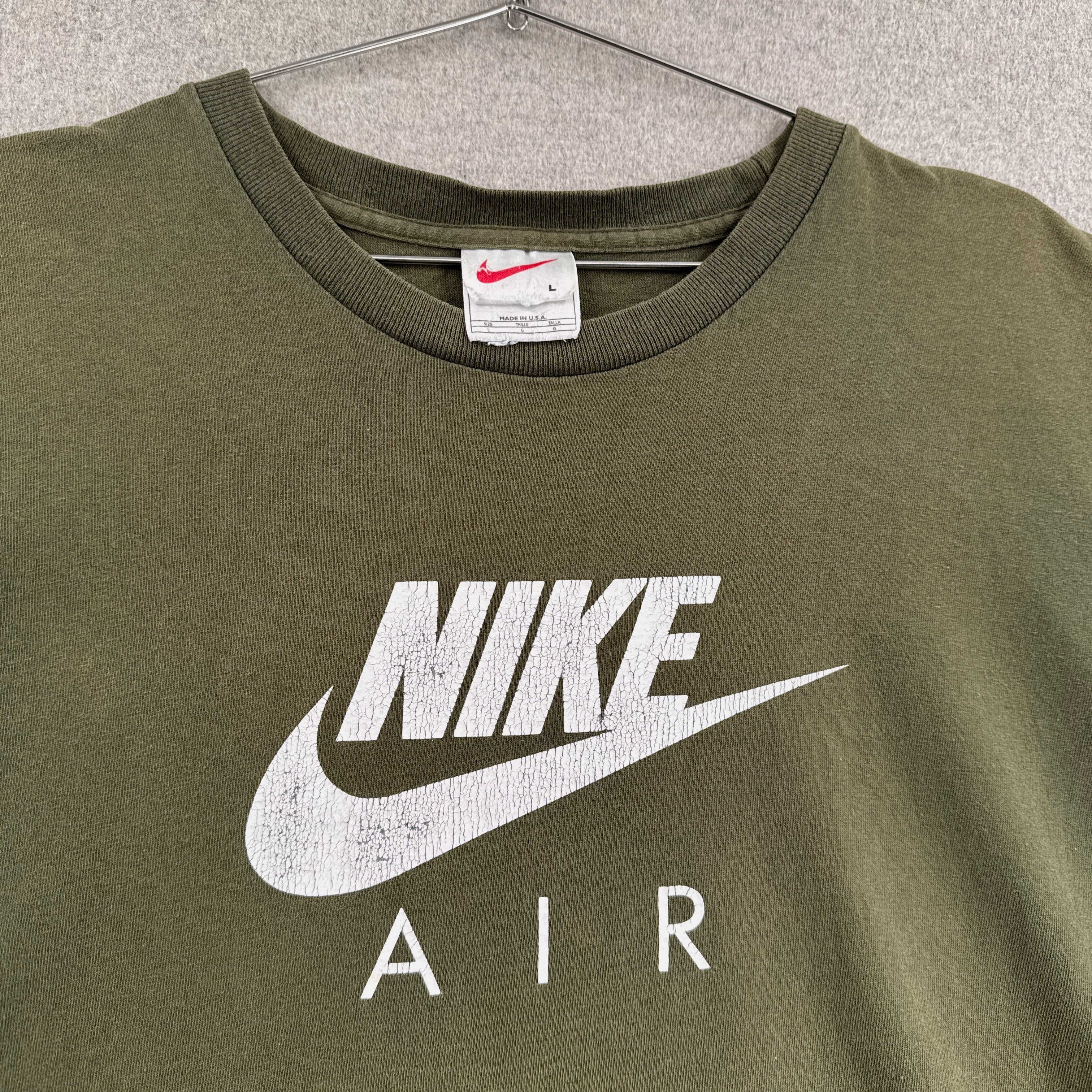 Green Nike Air t-shirt on a hanger with a visible brand label.