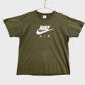 Green graphic tee top with Nike logo on a gray background