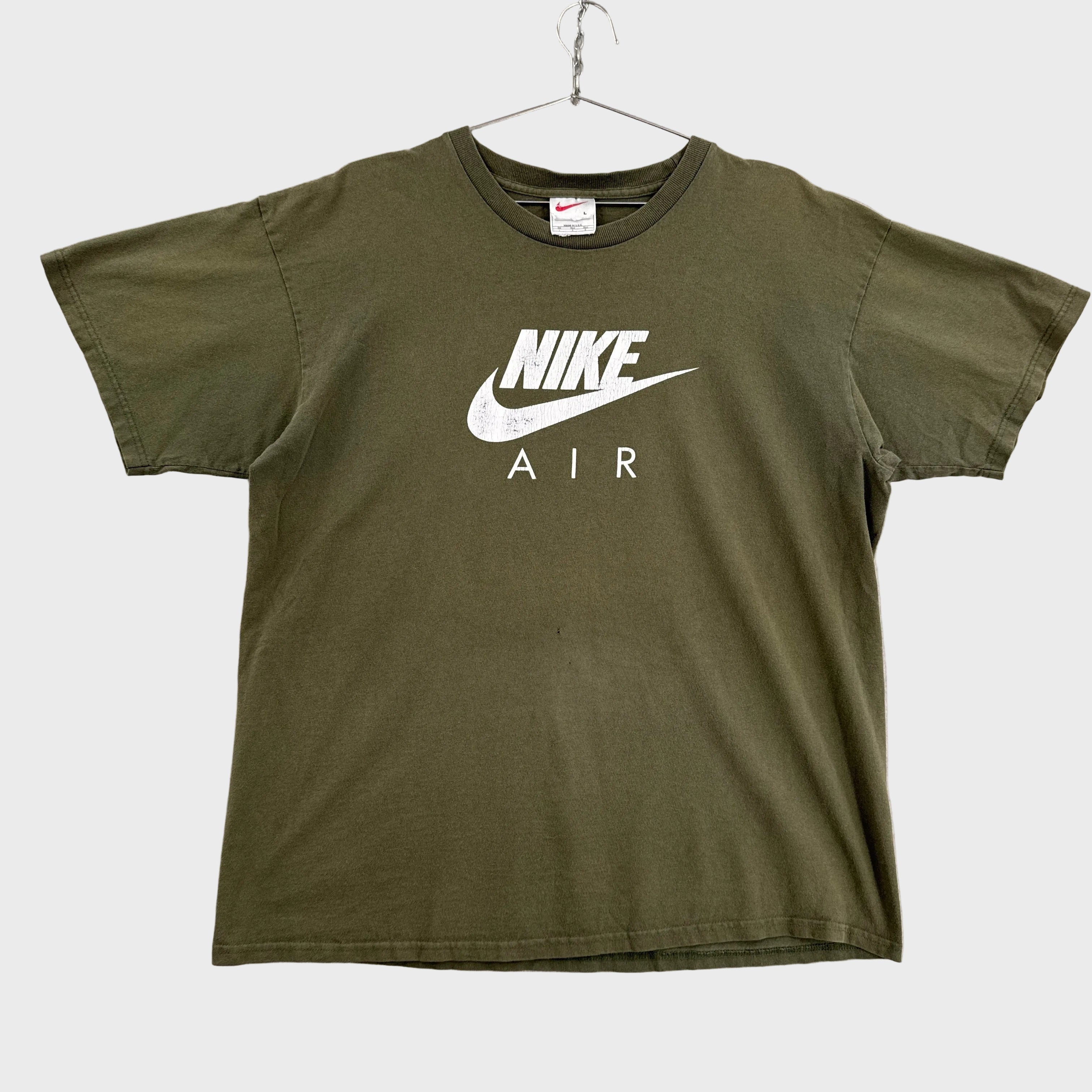 Green graphic tee top with Nike logo on a gray background
