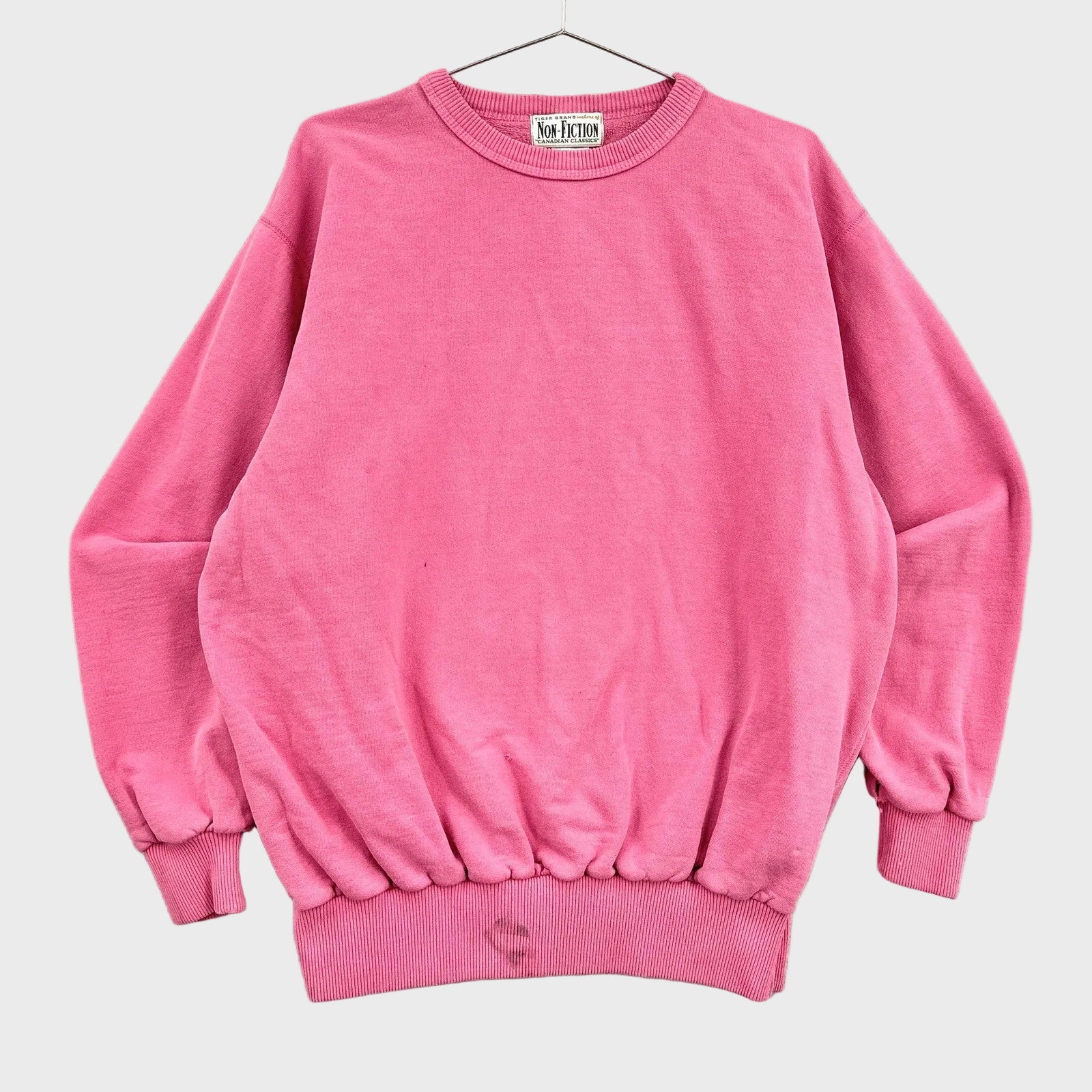 Pink blank sweatshirt on a hanger with a neutral background