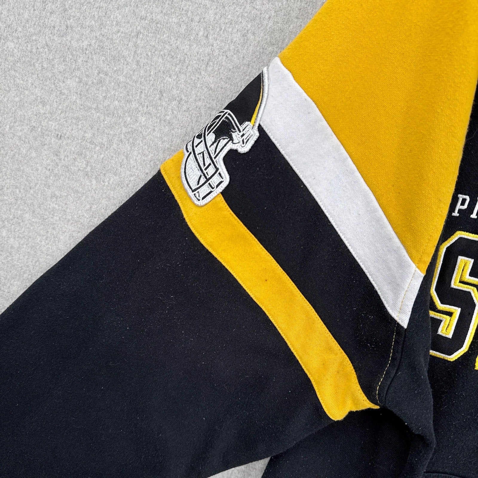 Close-up of a sports hoodie with black, yellow, and white colors on a gray background