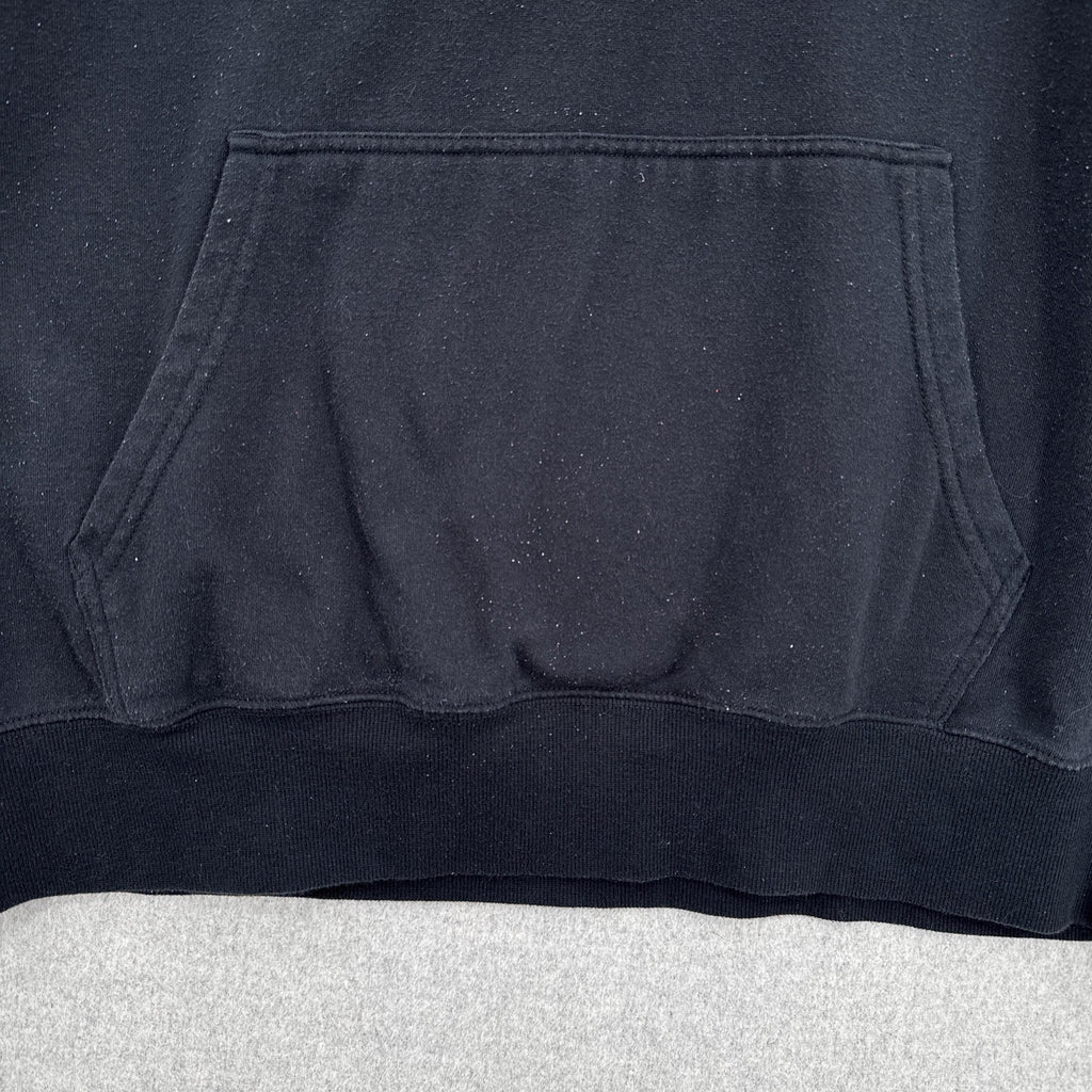 Close-up of a black hoodie with a pocket on a light gray surface