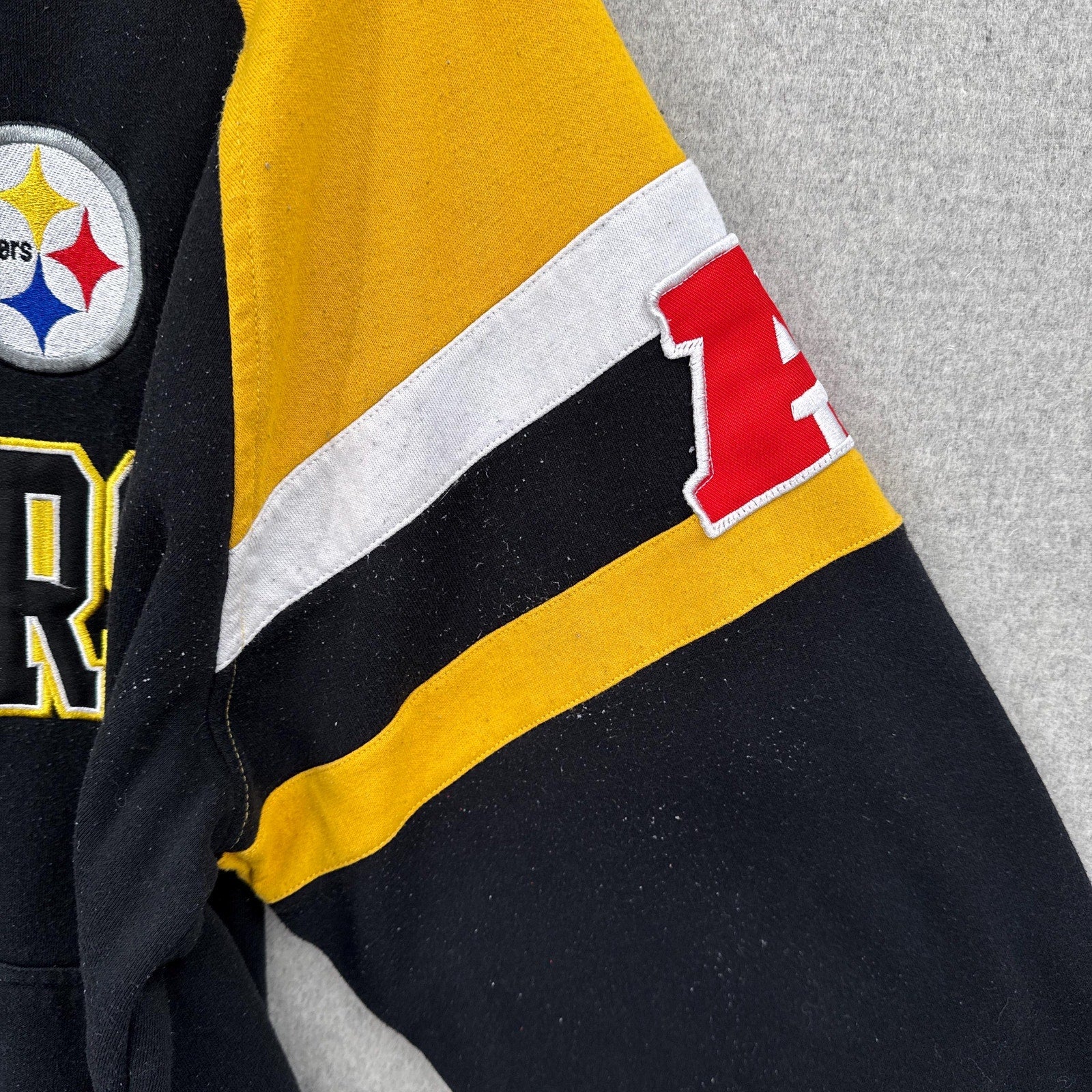 Close-up of a sports hoodie sleeve with logos and colors on a gray background