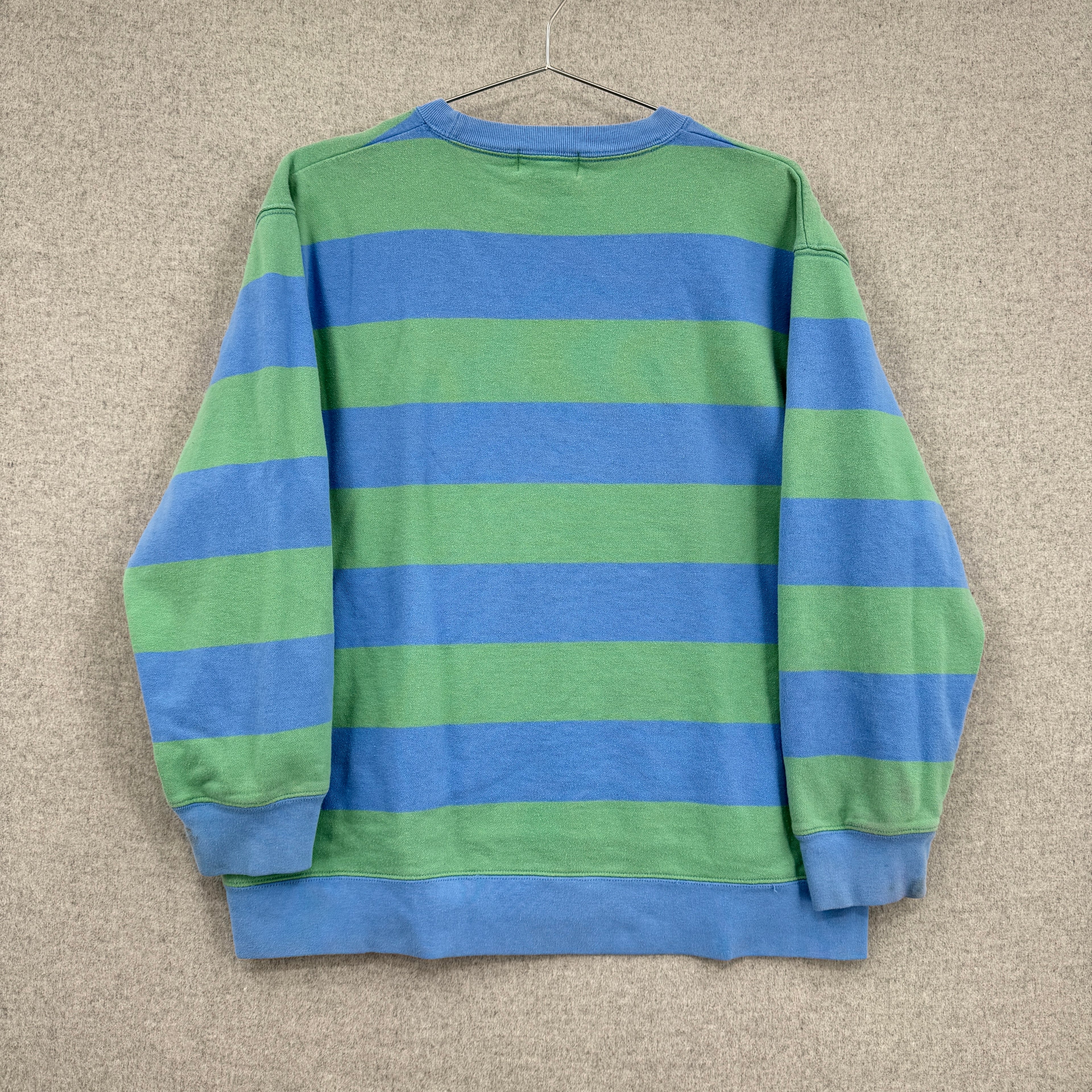 Blue and green striped sweater on a beige background