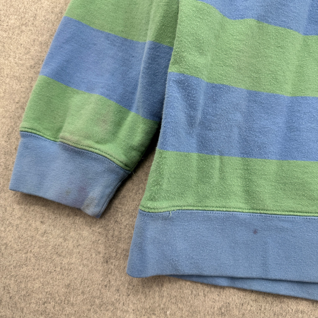 Blue and green striped fabric on a beige surface, stain on bottom hems
