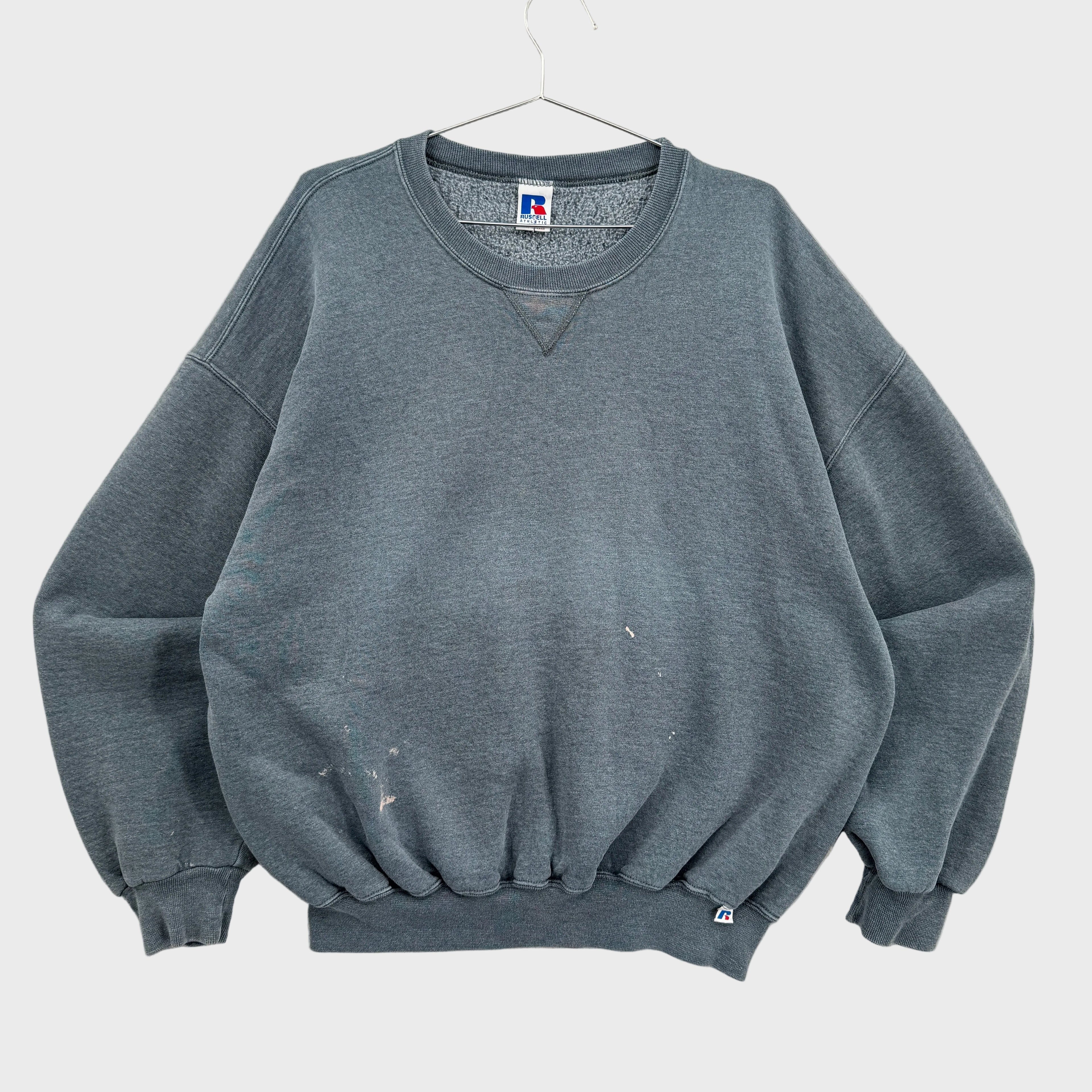 Gray sweatshirt on a hanger with a visible brand label against a neutral background