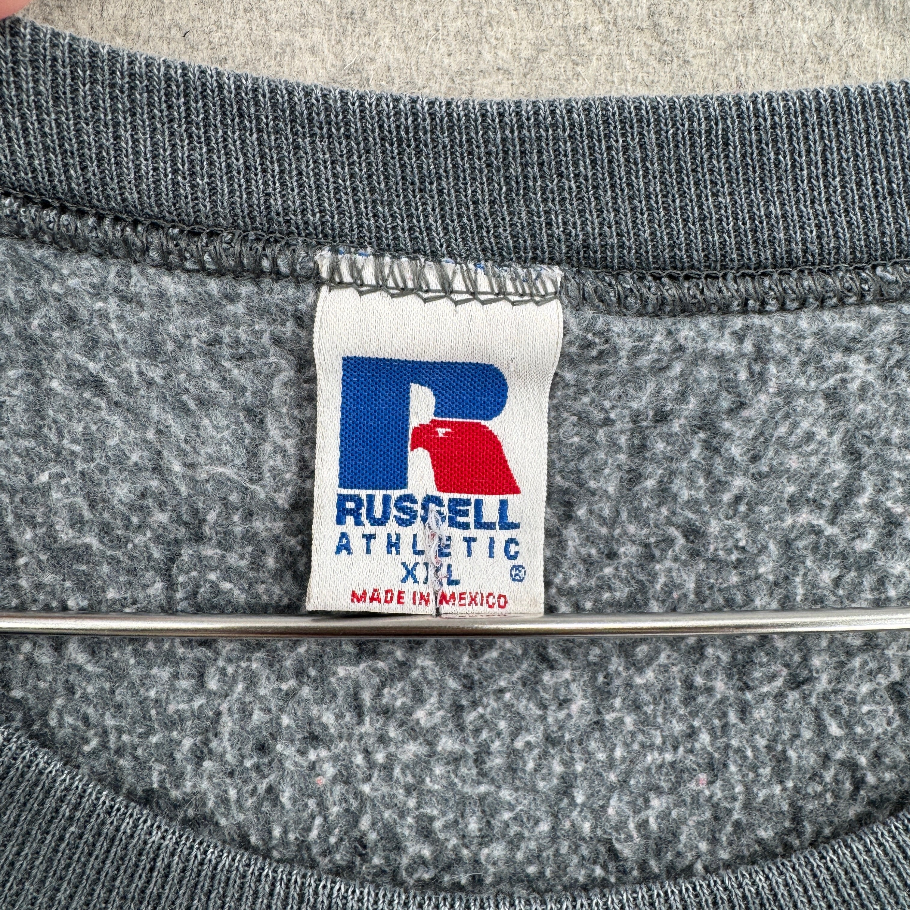 Gray sweatshirt with a Russell Athletic label on a textured gray background. Made in Mexico size 2XL
