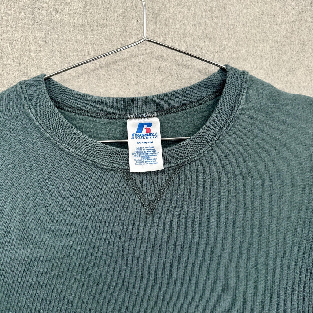 Greenish blue grey sweatshirt with a brand label on a hanger against a neutral background