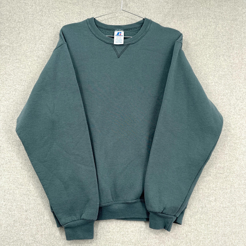 Green sweatshirt on a hanger with a visible brand label against a neutral background