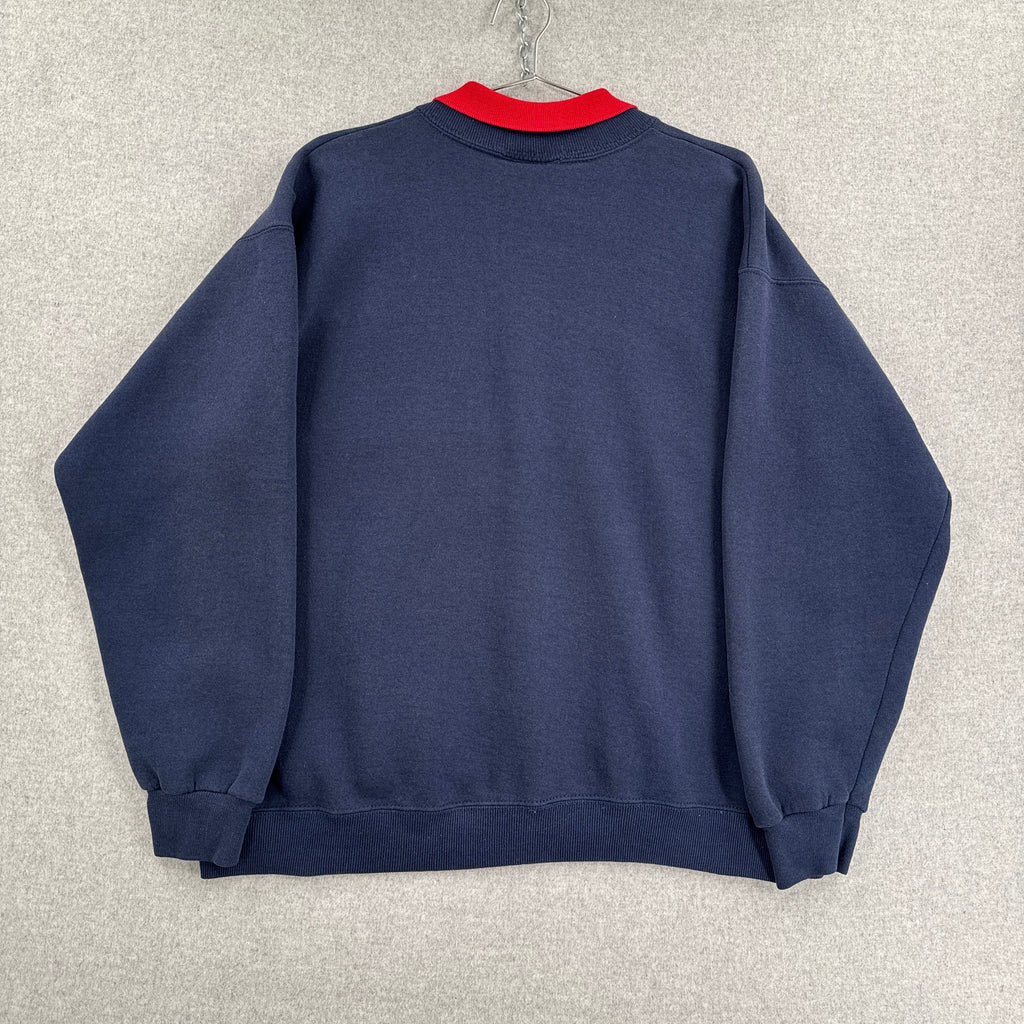Folded navy blue shirt with a red sleeve on a light gray surface