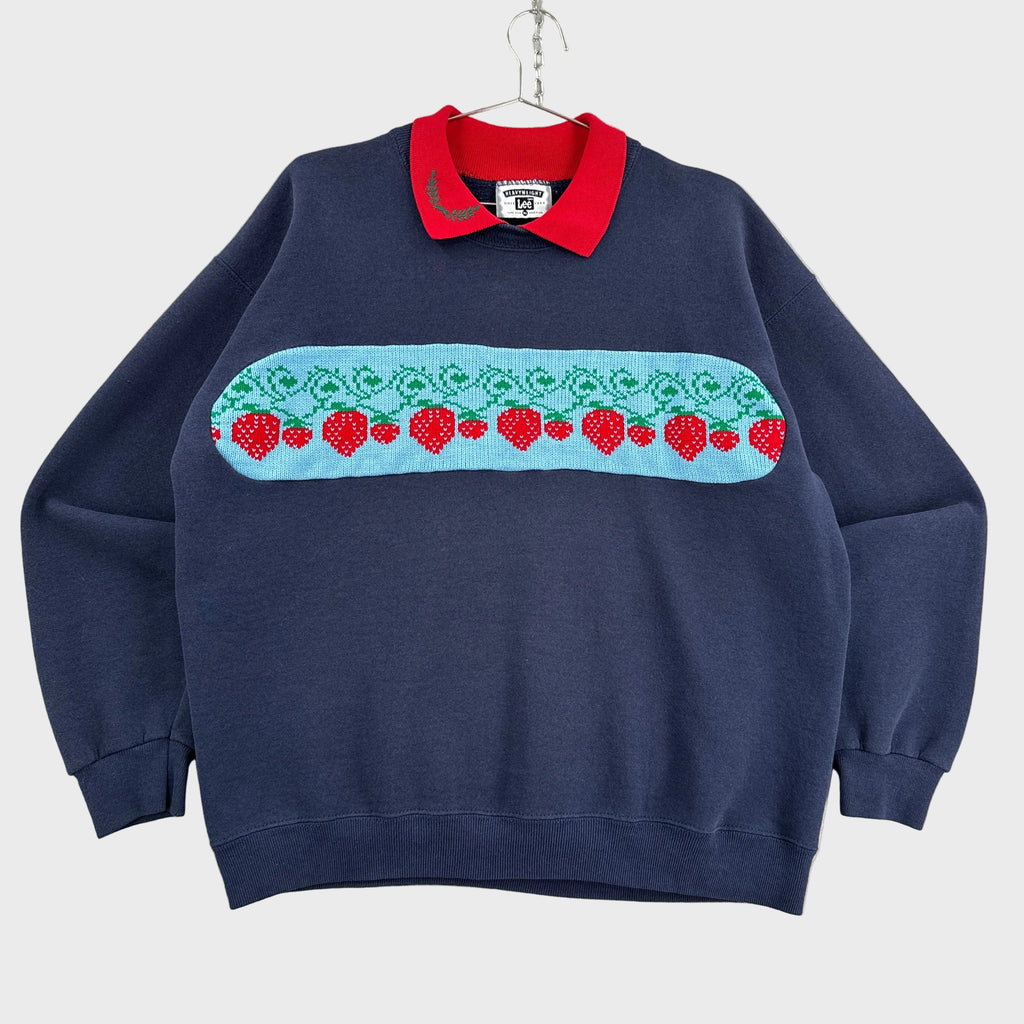 Navy blue sweatshirt with a colorful strawberry pattern on a gray surface