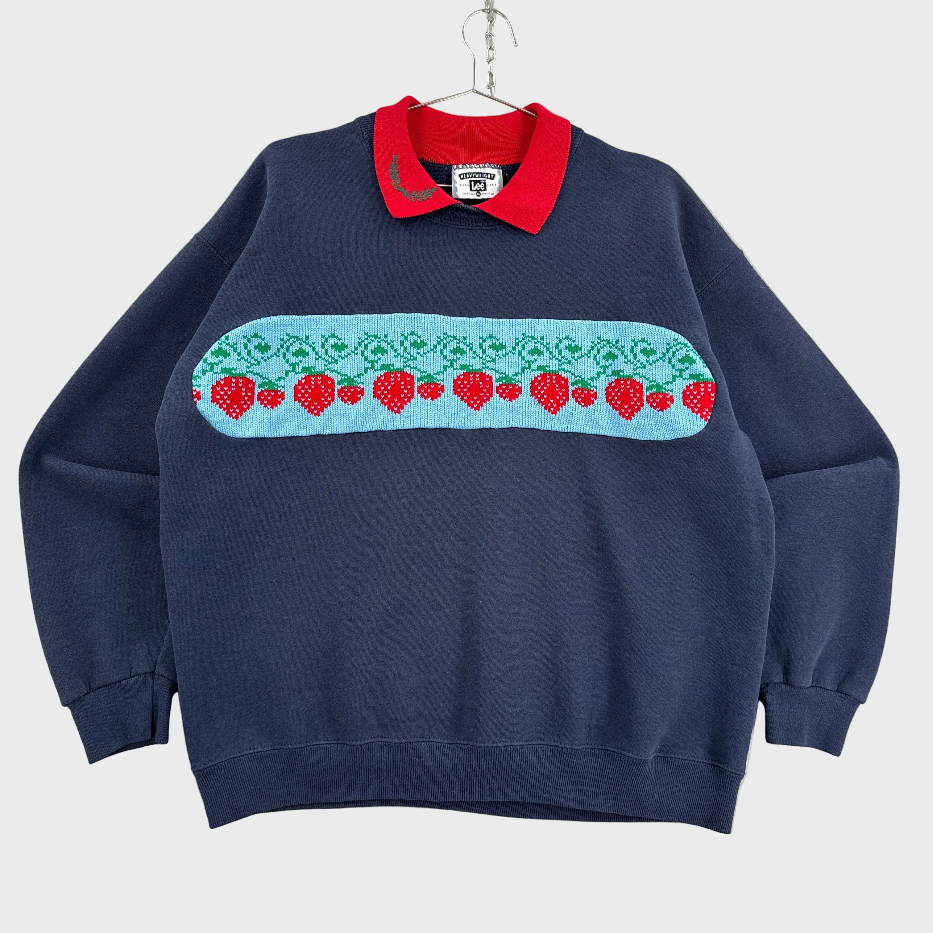 Navy blue sweatshirt with a colorful strawberry pattern on a gray surface