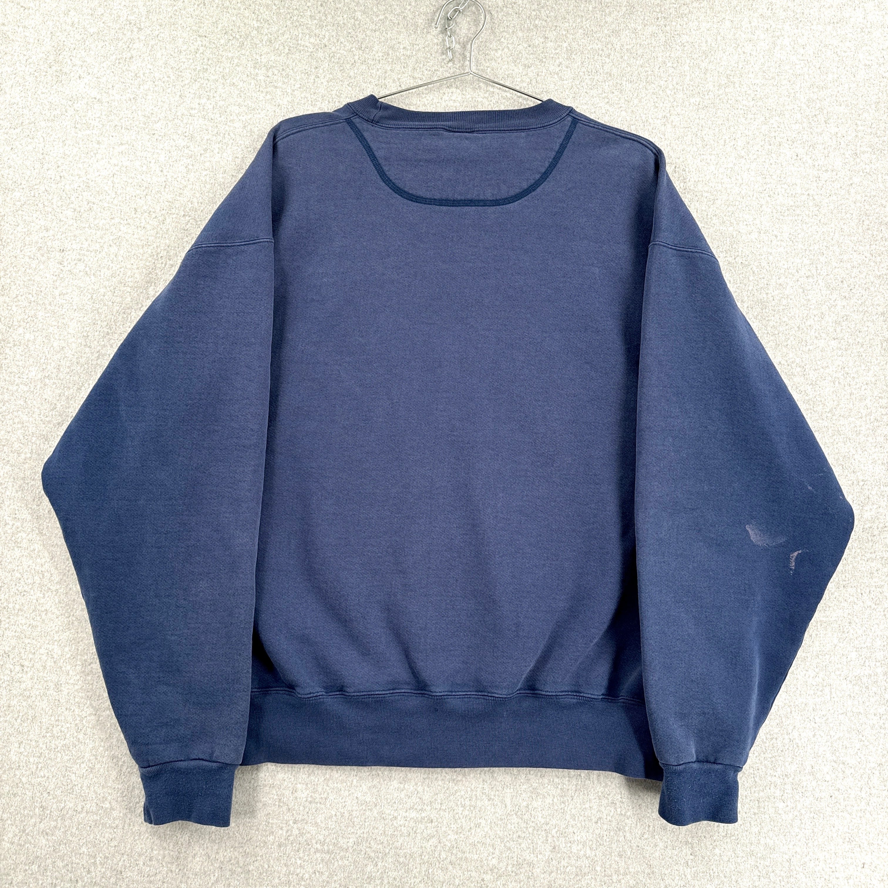 Blue sweatshirt on a hanger against a textured white background