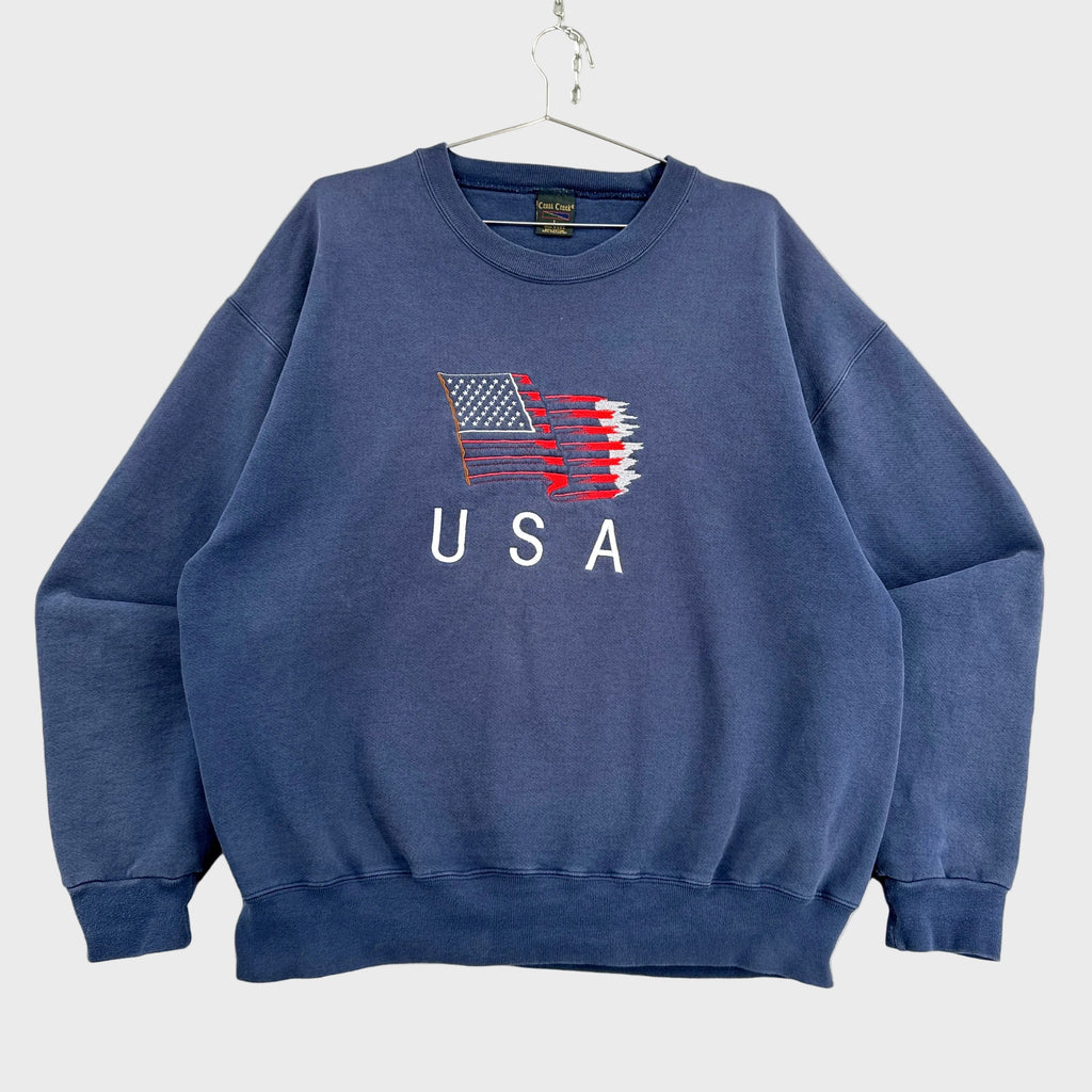 Blue sweatshirt with USA flag design on a textured surface