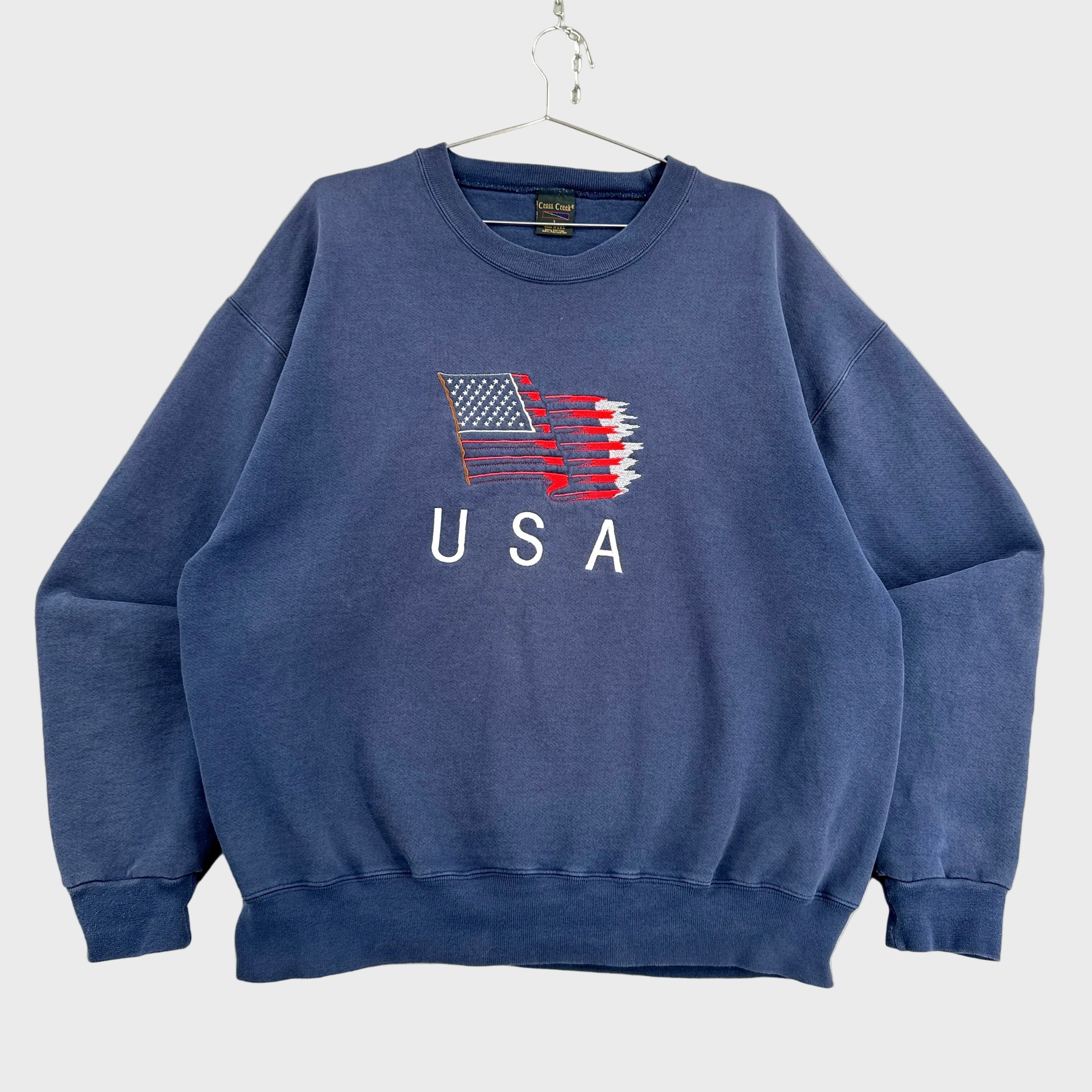 Blue sweatshirt with USA flag design on a textured surface