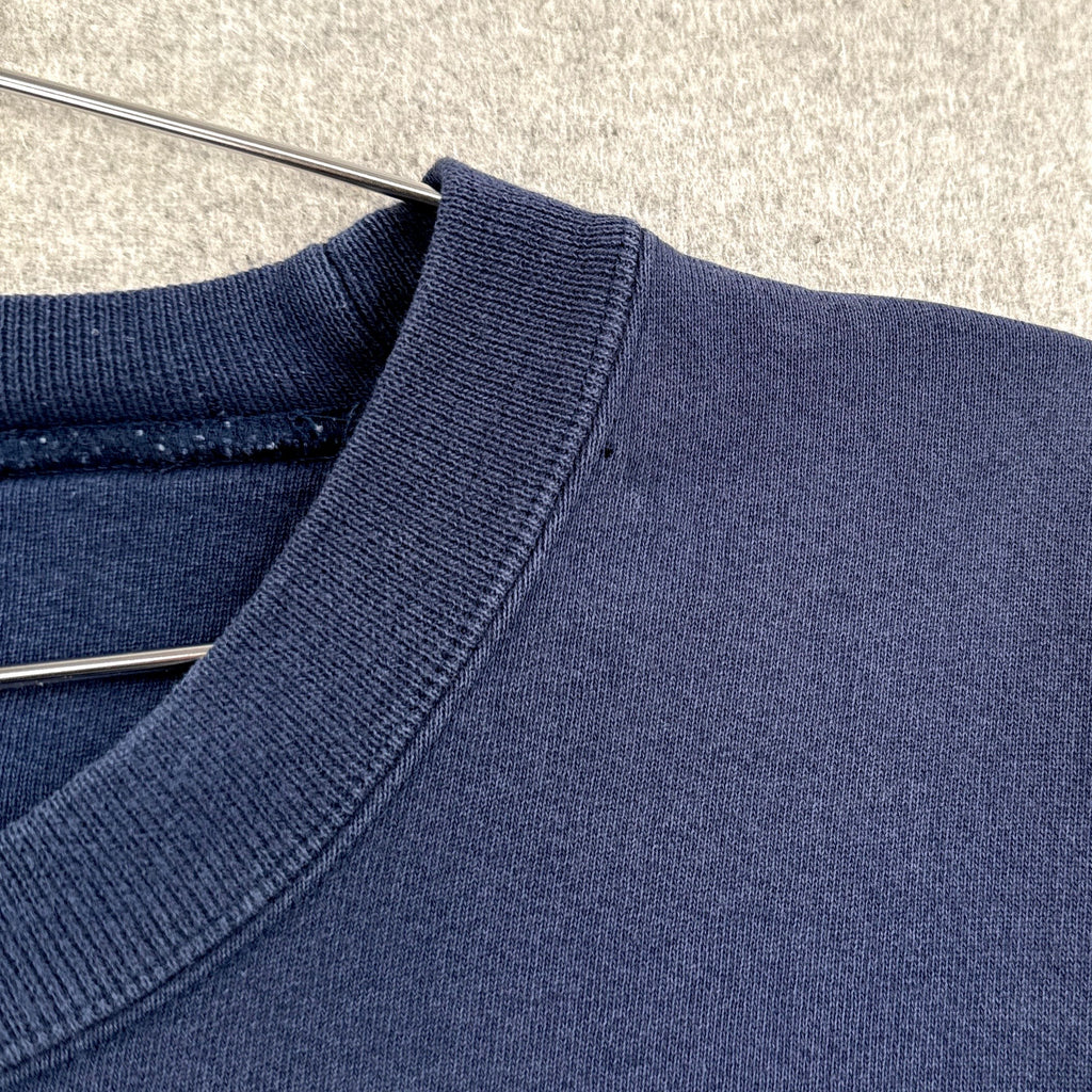 Close-up of a blue sweater on a hanger with a neutral background. small hole around collar