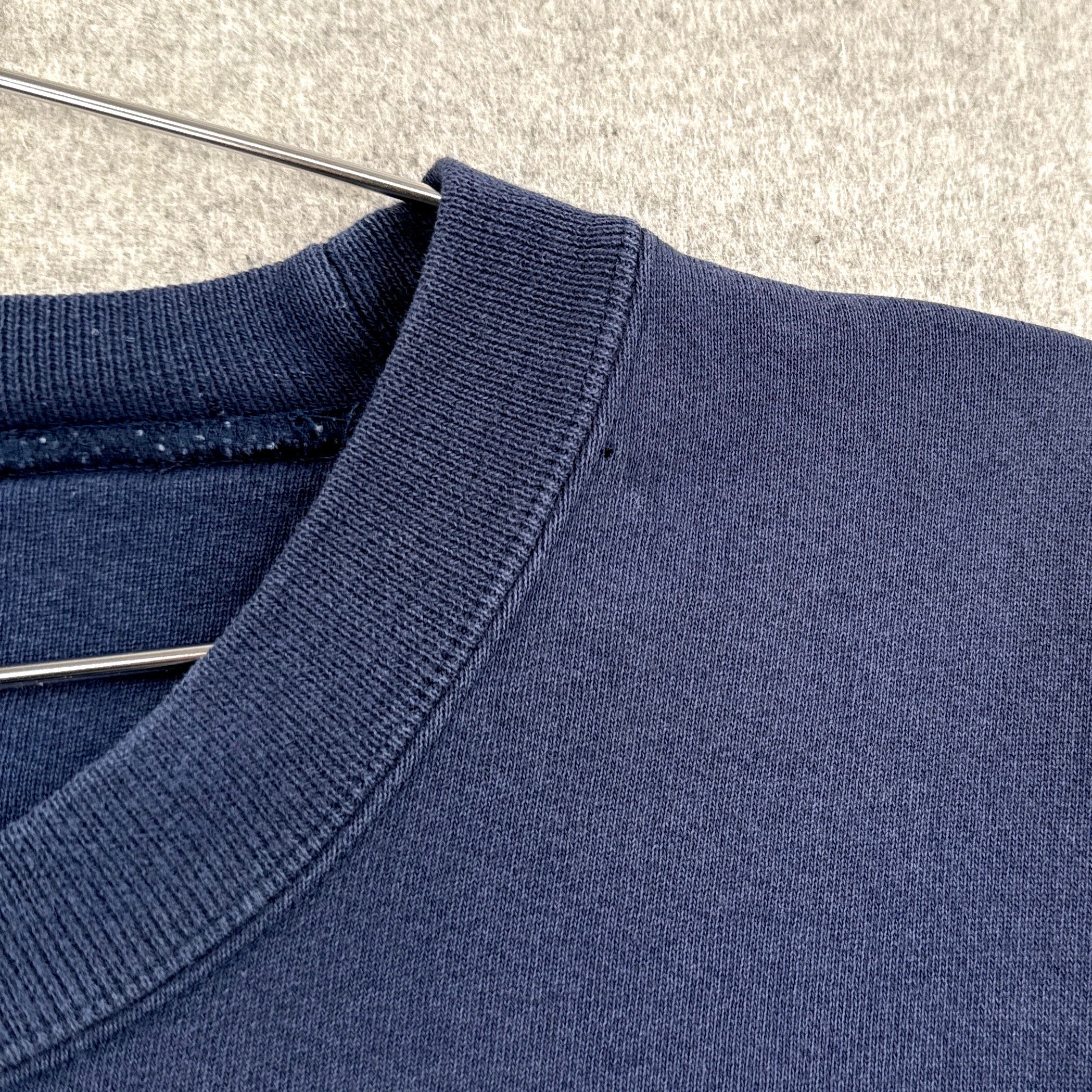 Close-up of a blue sweater on a hanger with a neutral background. small hole around collar