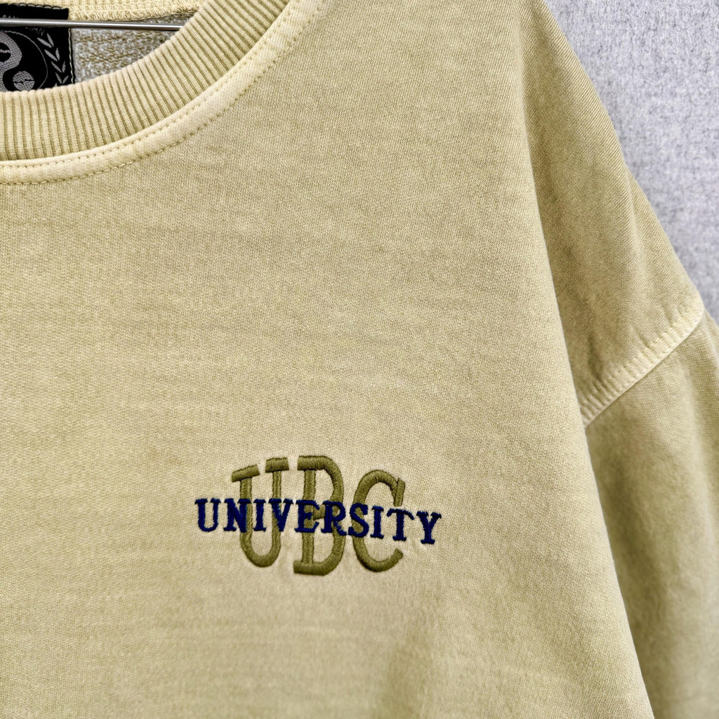 faded greenish yellow sweatshirt with 'UBC' embroidered on it, hanging against a light gray background.
