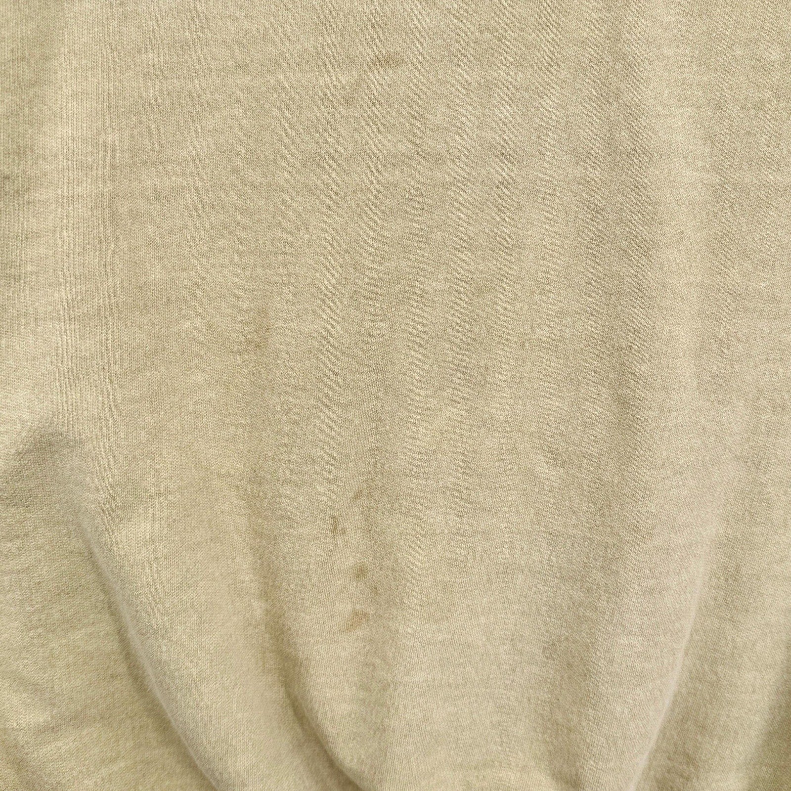 Close-up of yellow beige fabric with visible texture and stain spots
