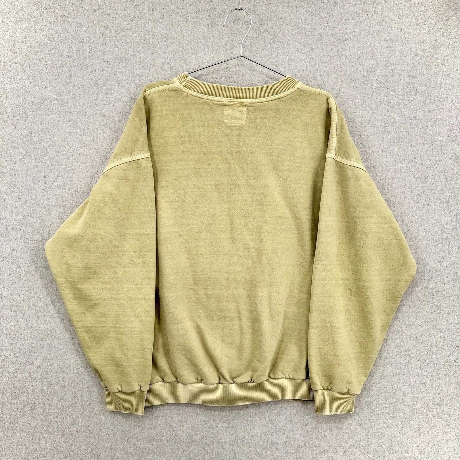 yellowish green sweatshirt on a hanger against a gray background