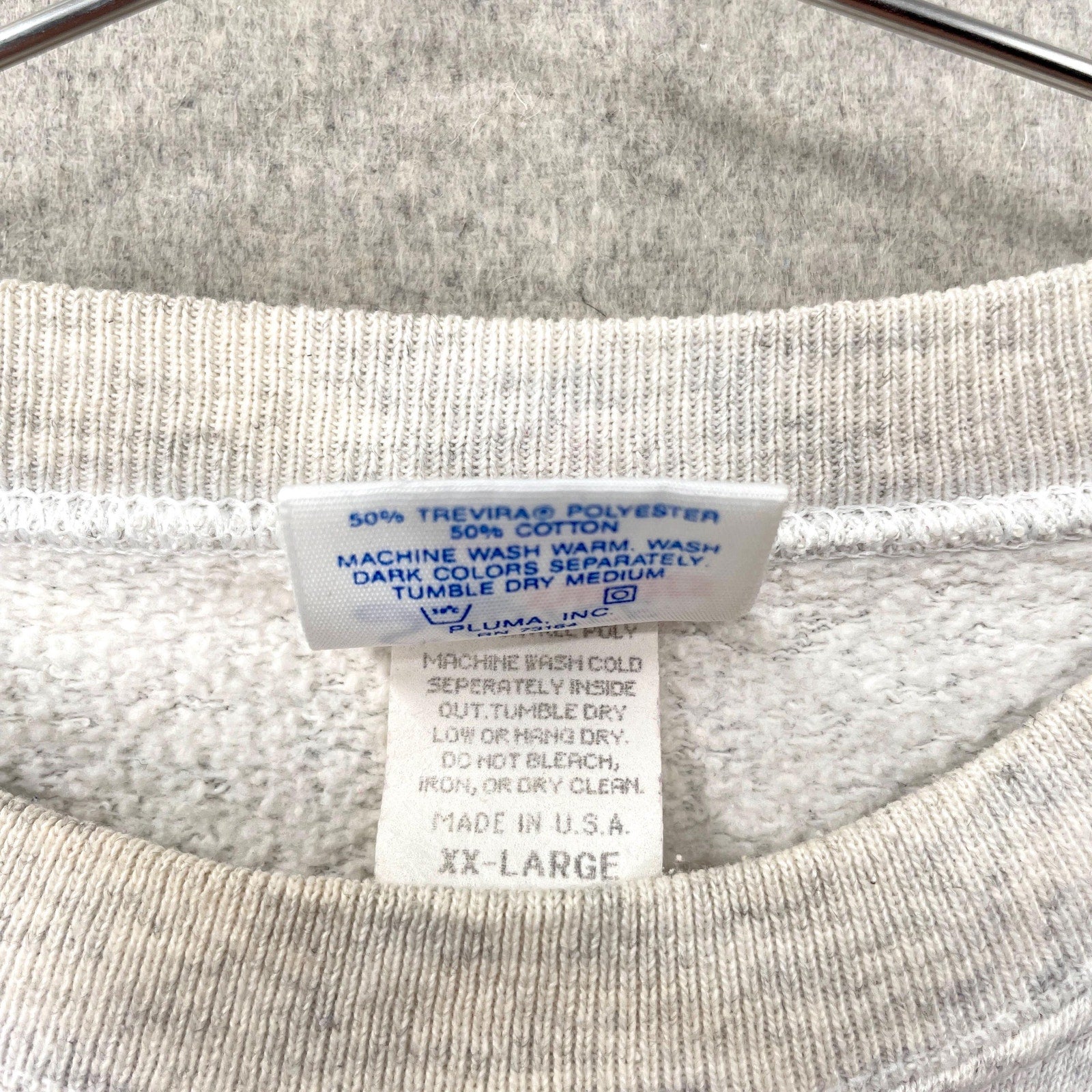 Close-up of a clothing label on a gray shirt with visible text. made in USA 2XL