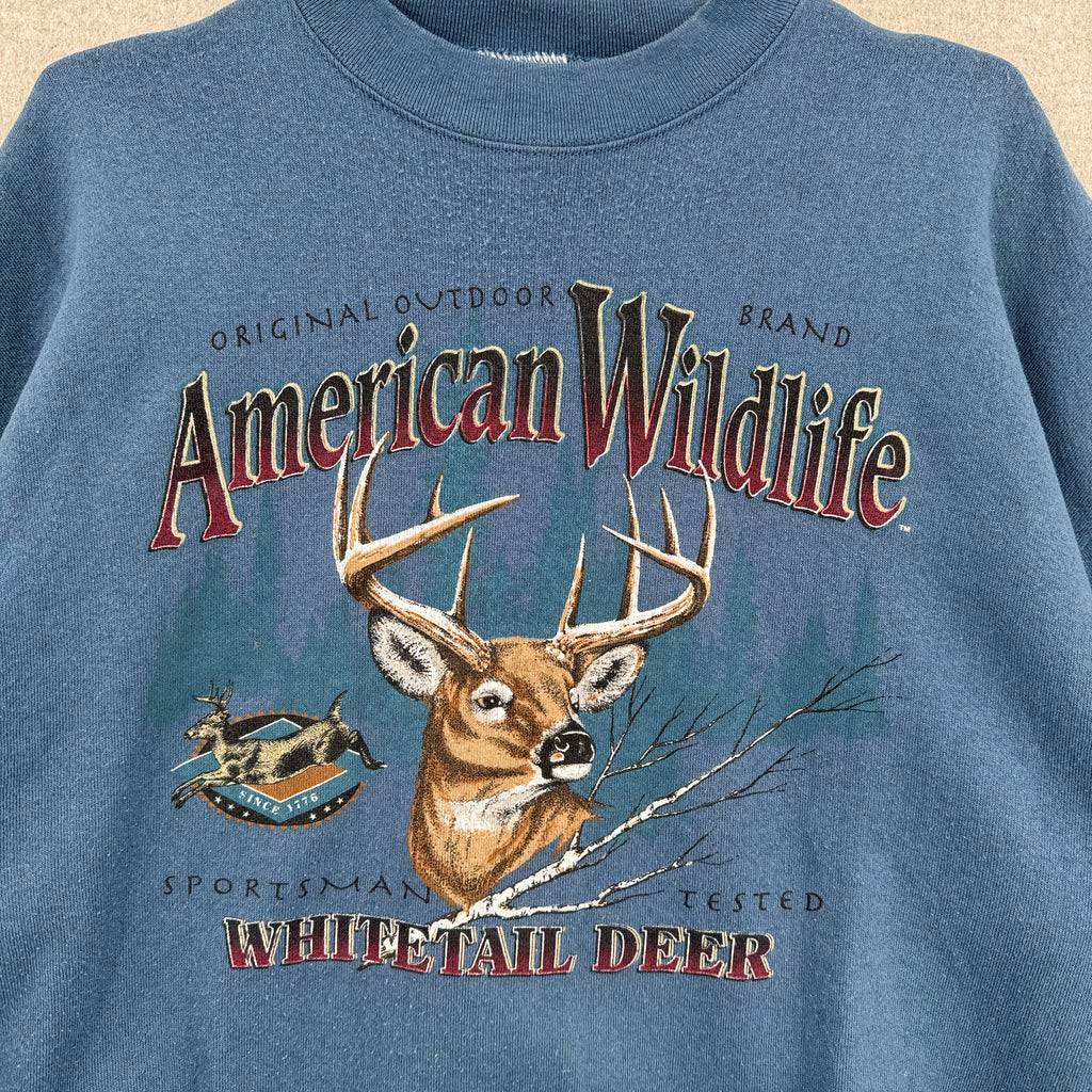 Blue sweatshirt with 'American Wildlife' and 'Whitetail Deer' graphic on a beige background