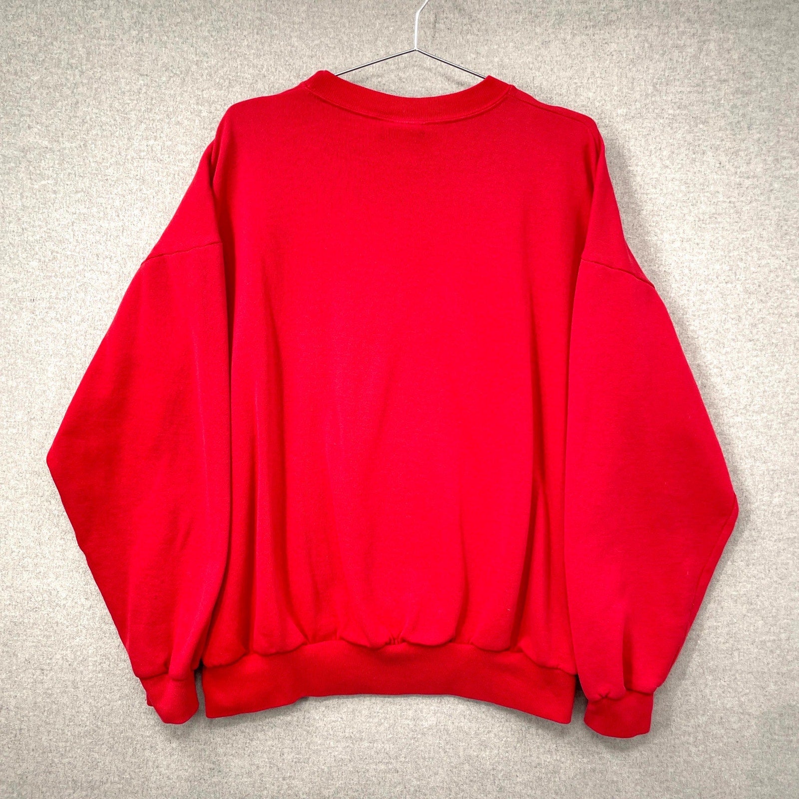Red sweatshirt on a hanger against a gray background