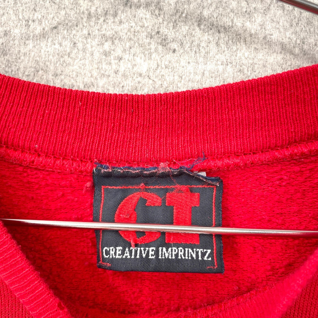 Close-up of a red garment with a 'Creative Imprintz' label on a gray background