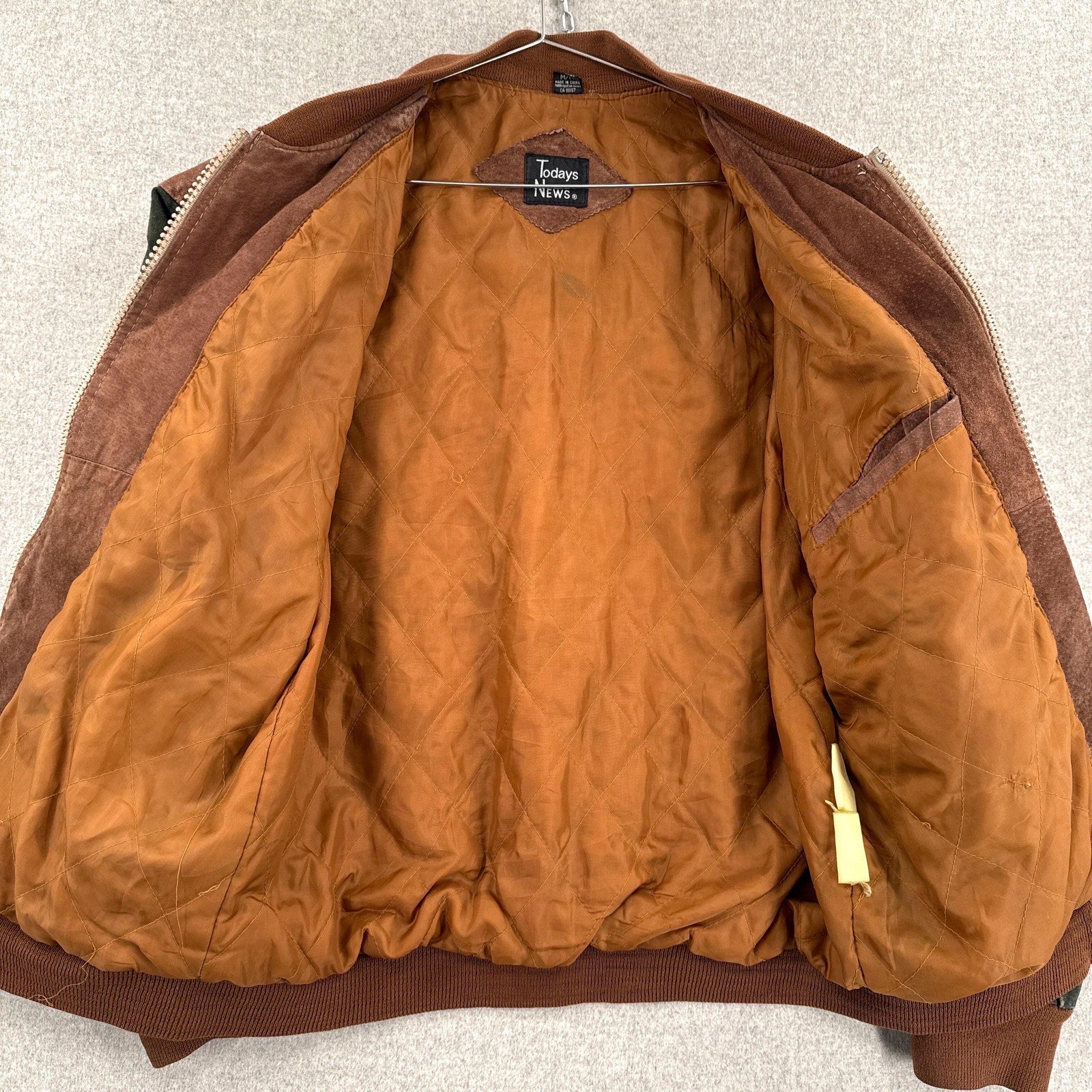 Brown jacket with a visible brand tag on a neutral background