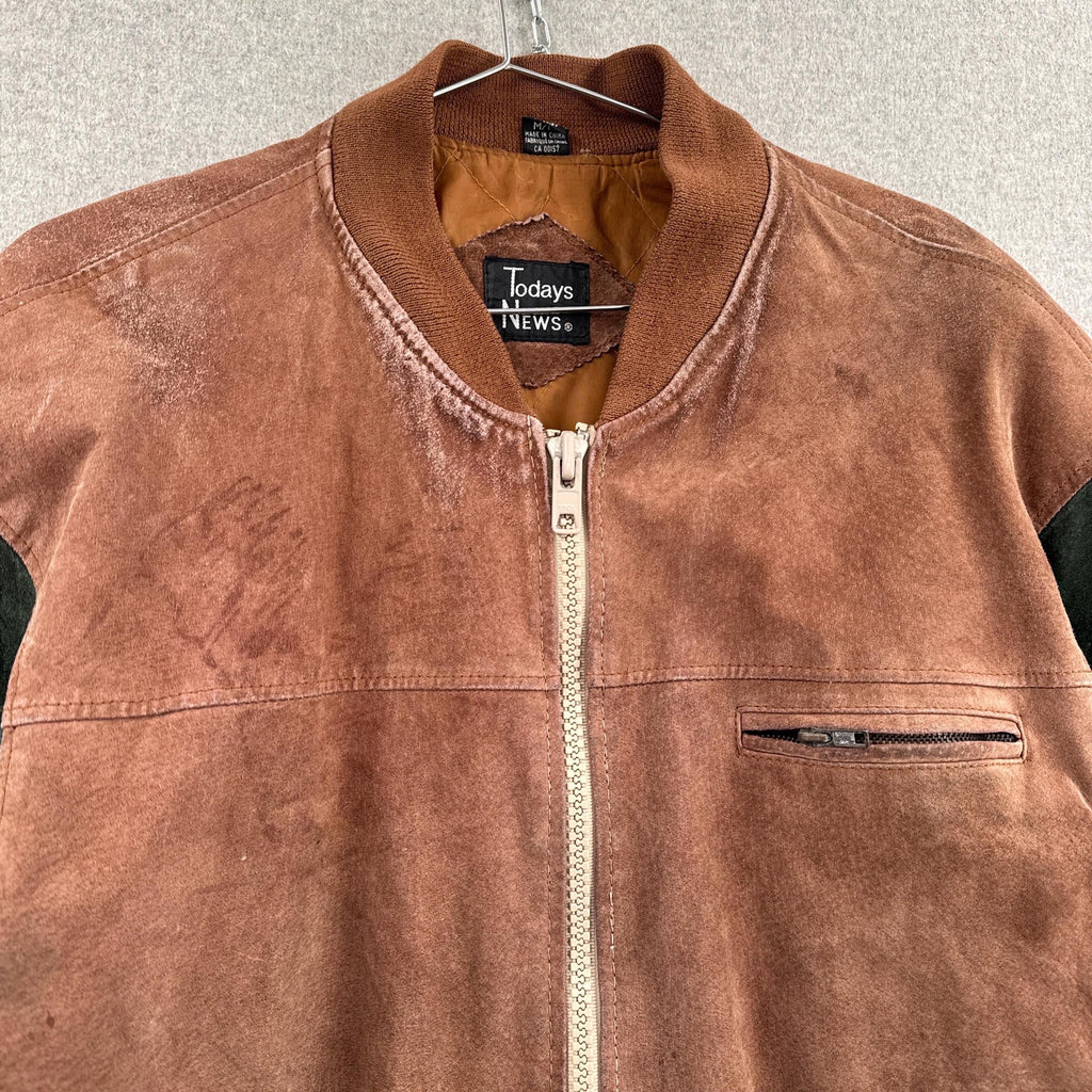 Brown jacket with a visible brand label on a hanger against a neutral background