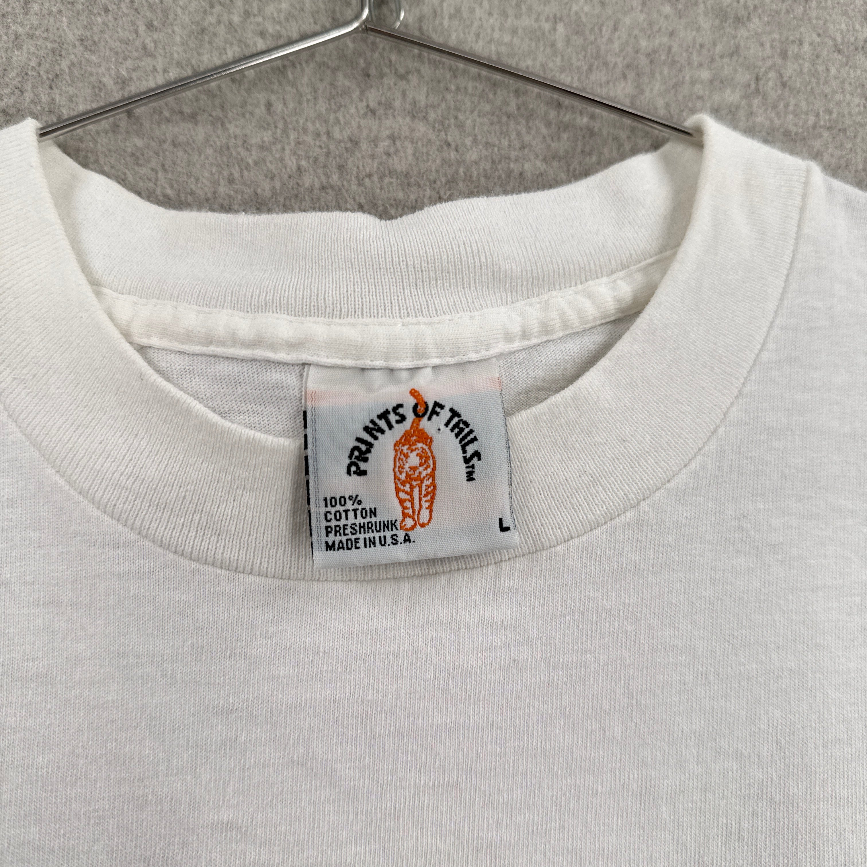 Close-up of a white hoodie with a brand label on a gray background. Tag is size Large, made in USA, 100% cotton preshrunk