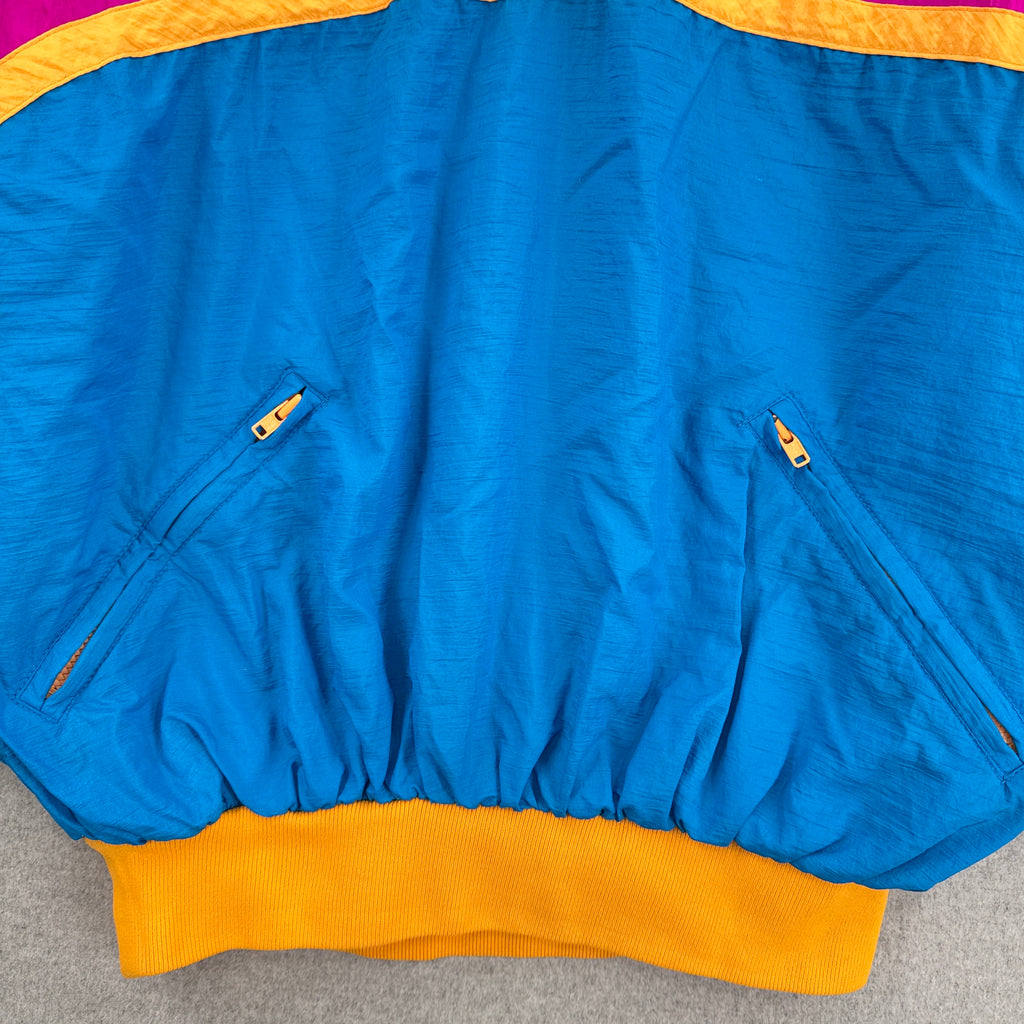 Blue jacket with orange trim on a gray surface. 2 zipper pockets