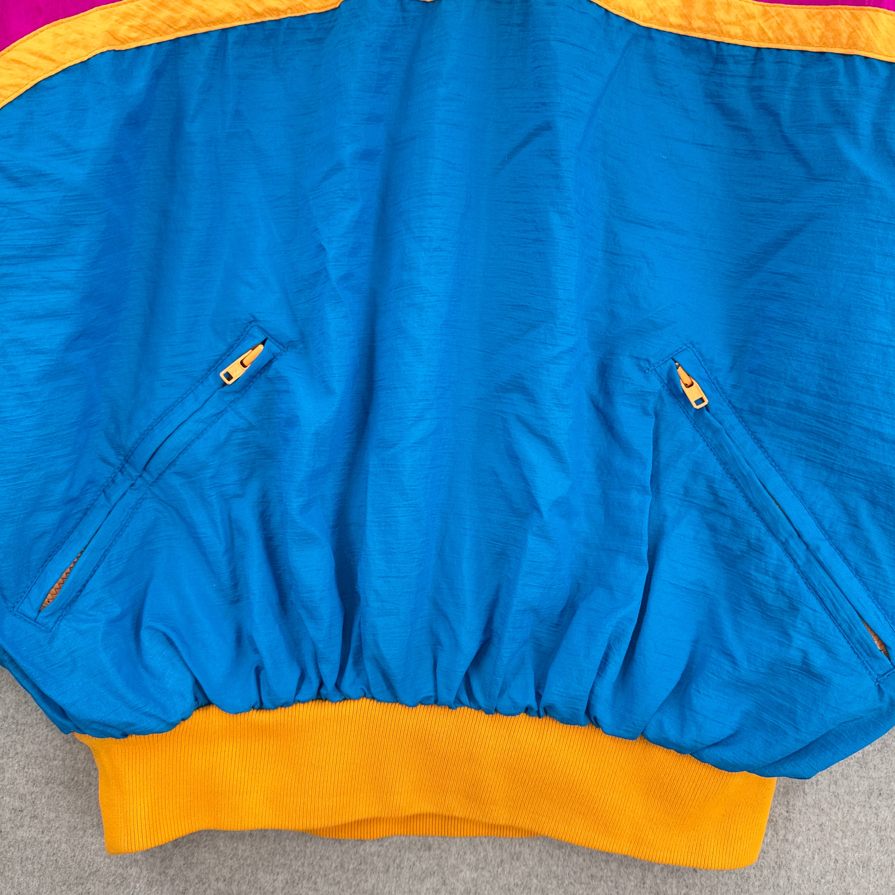 Blue jacket with orange trim on a gray surface. 2 zipper pockets