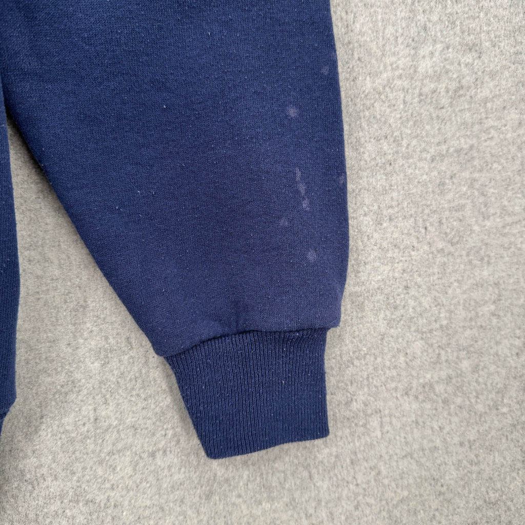 Close-up of a blue fabric sleeve on a gray background. Shows several light blue stain spots on the bottom of the sleeve