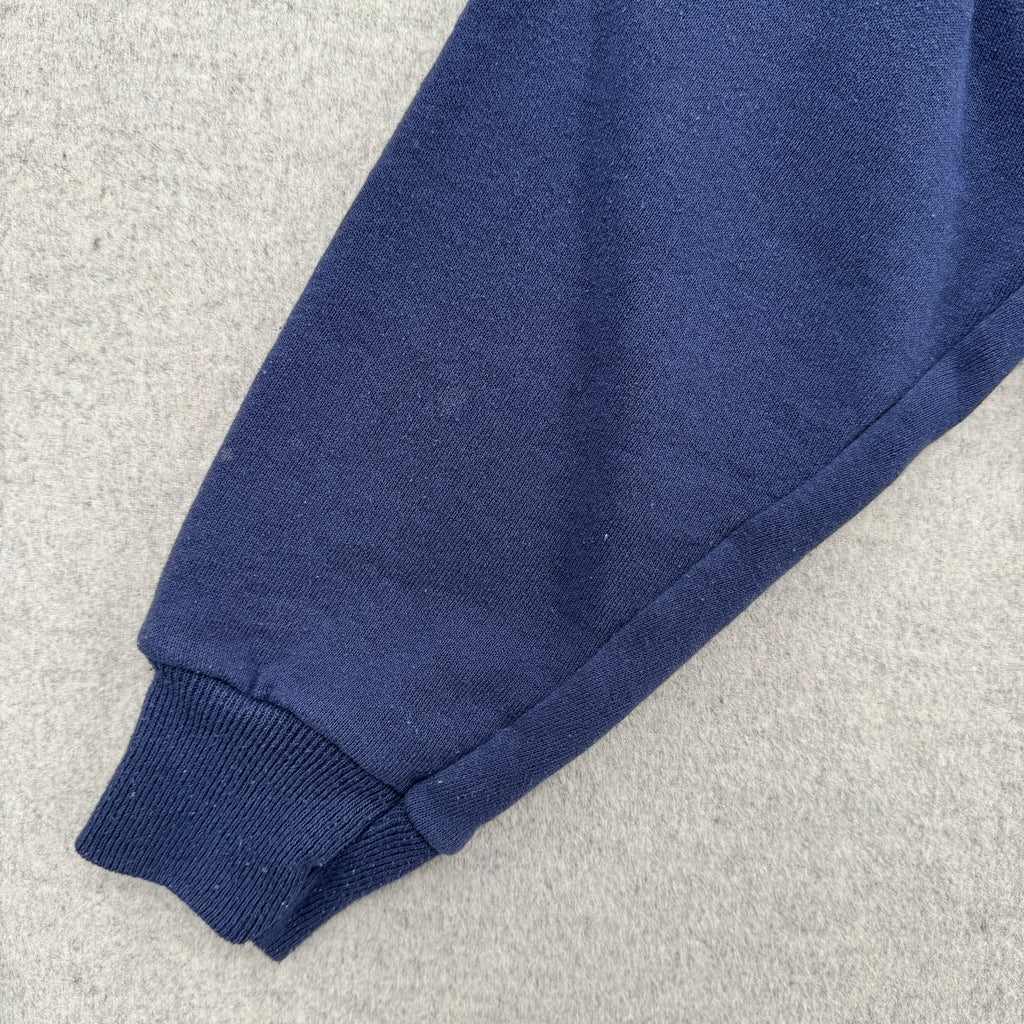 Close-up of a blue fabric sleeve on a light gray background. Shows 2-3 small lightened blue stain spots.
