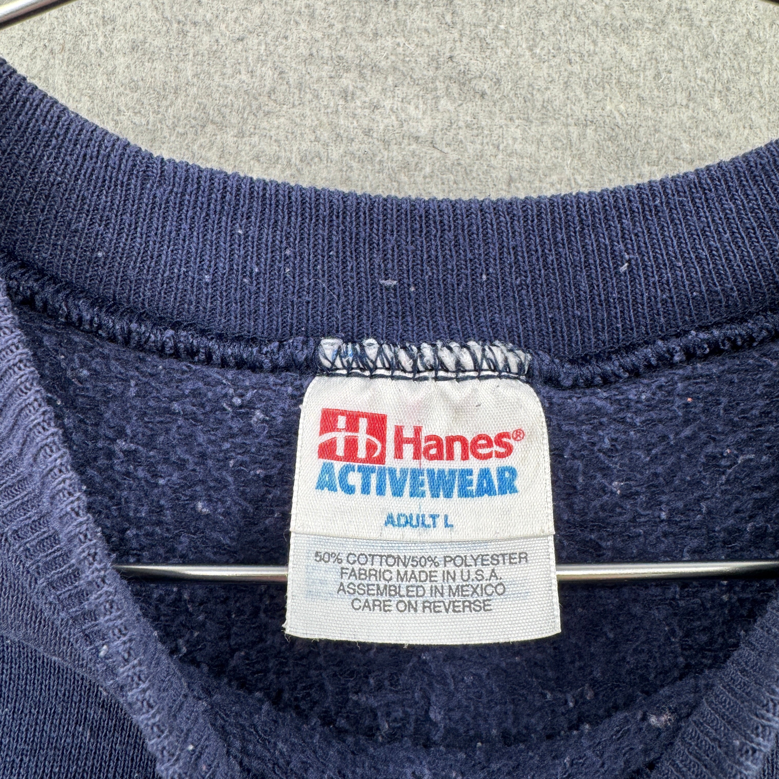Hanes ActiveWear label on a navy blue garment with a gray background. Adult Large, 50/50% cotton/polyester blend.
