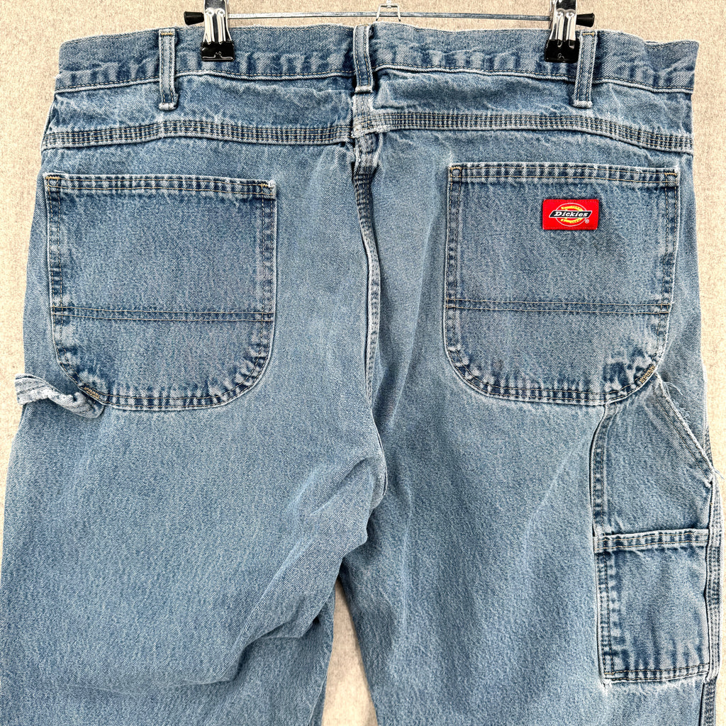 Pair of light blue jeans with a Dickies logo on a beige background