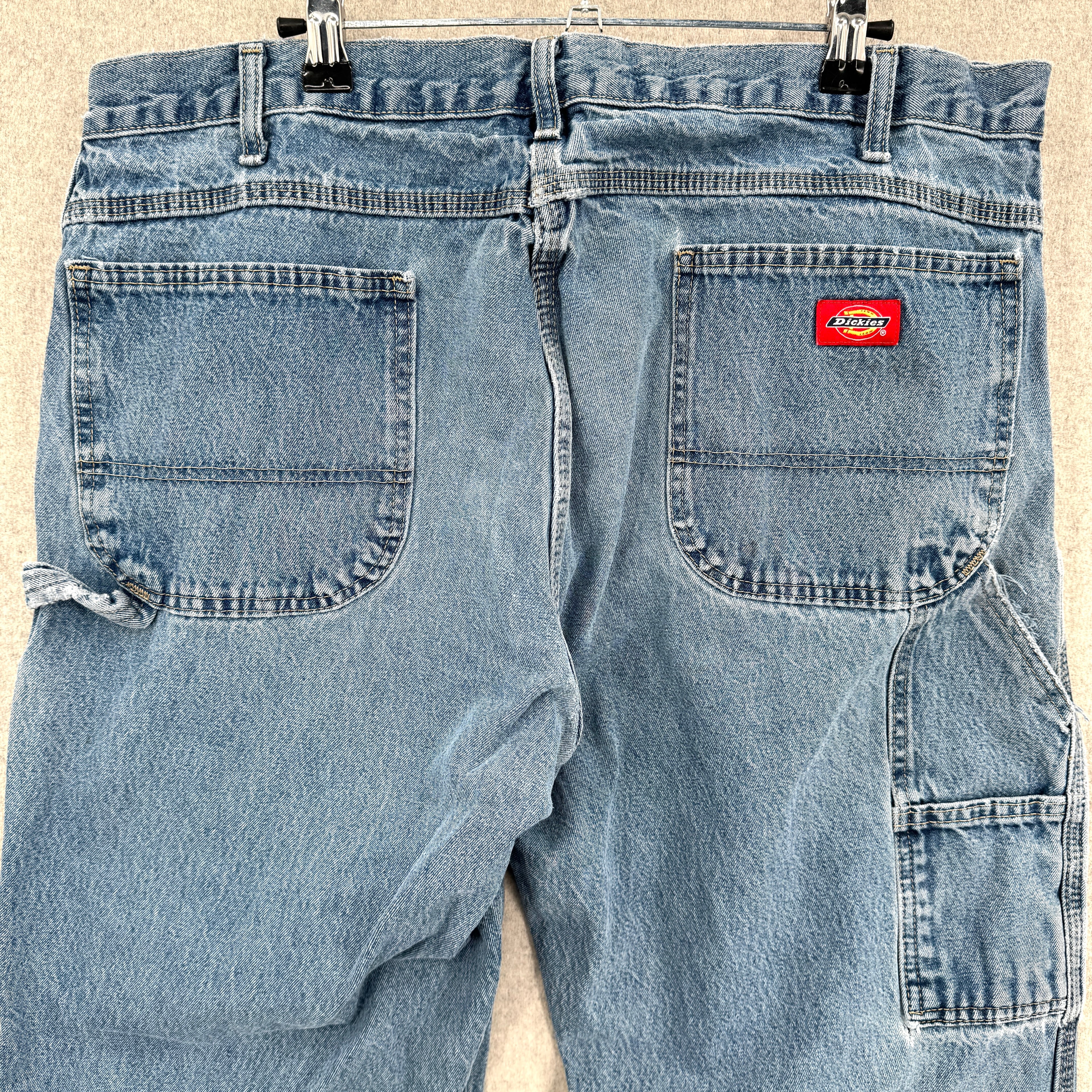 Pair of light blue jeans with a Dickies logo on a beige background