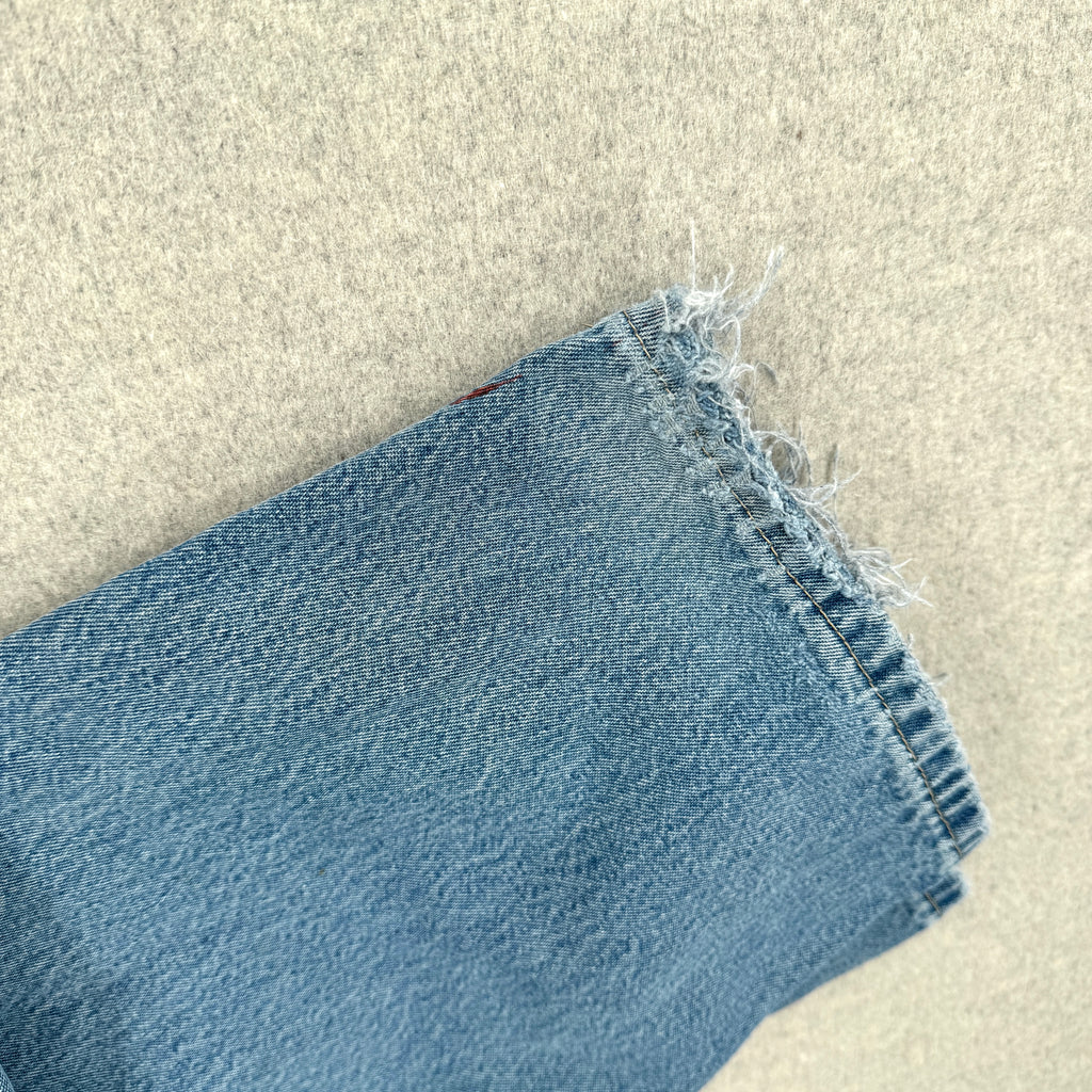 Close-up of blue denim fabric on a beige surface. frayed bottom hem 