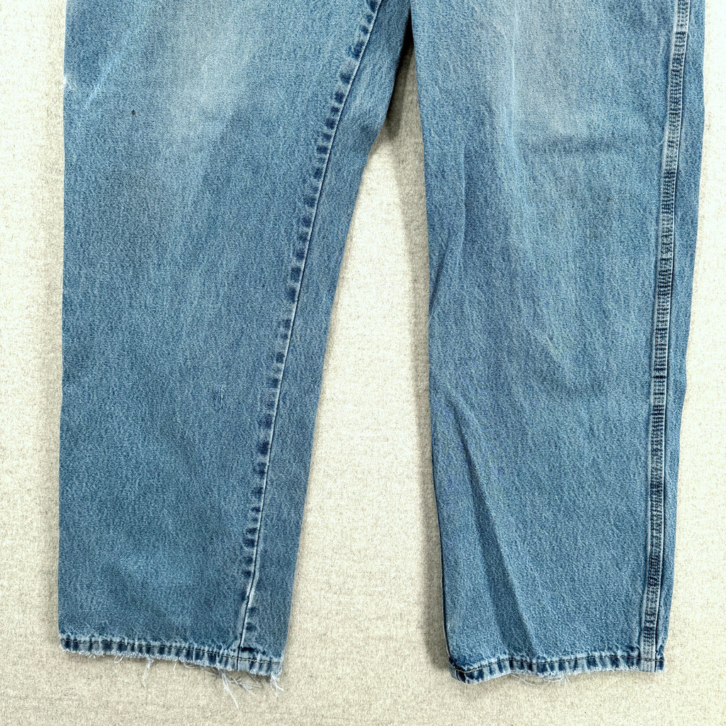 Pair of blue jeans on a textured beige surface, bottom