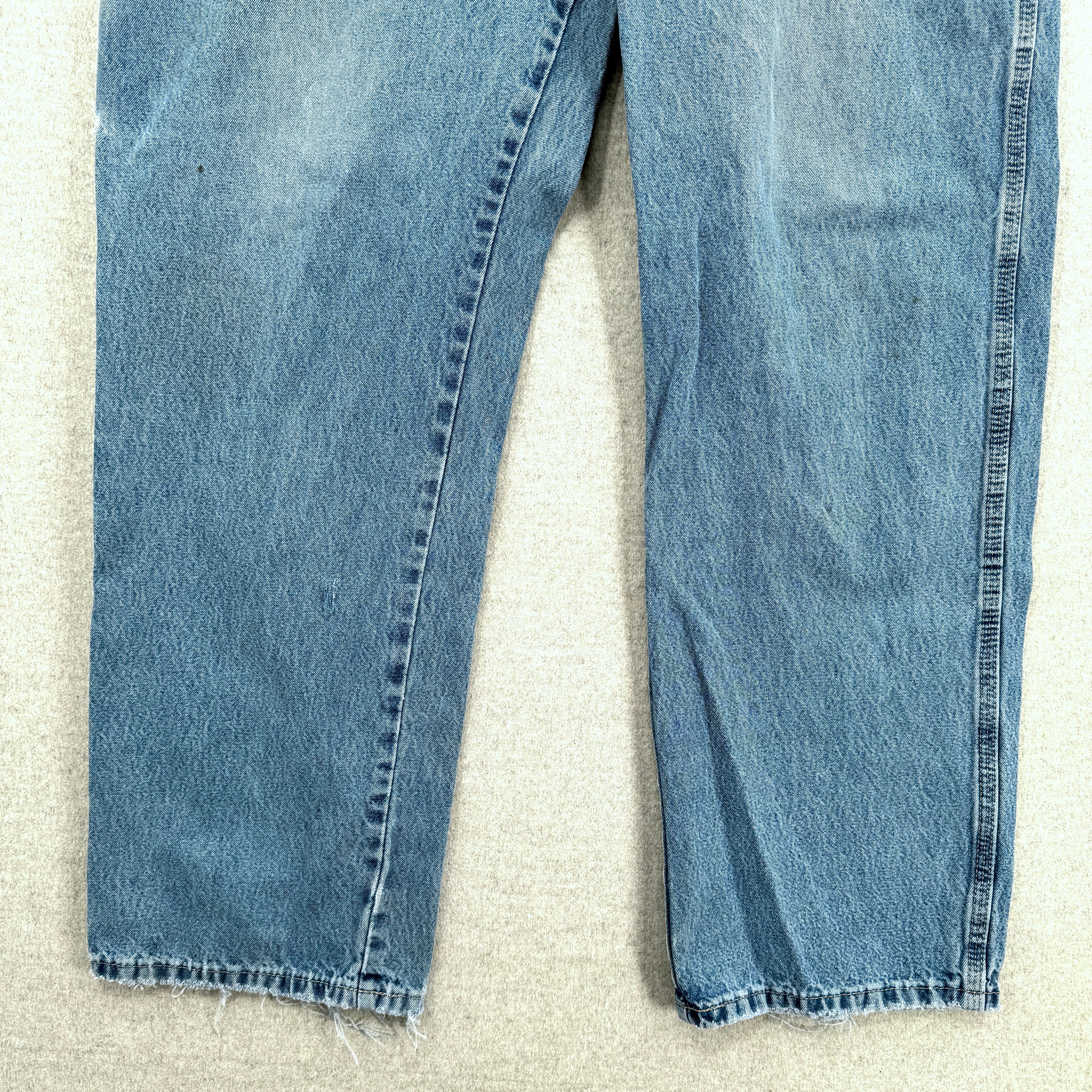 Pair of blue jeans on a textured beige surface, bottom
