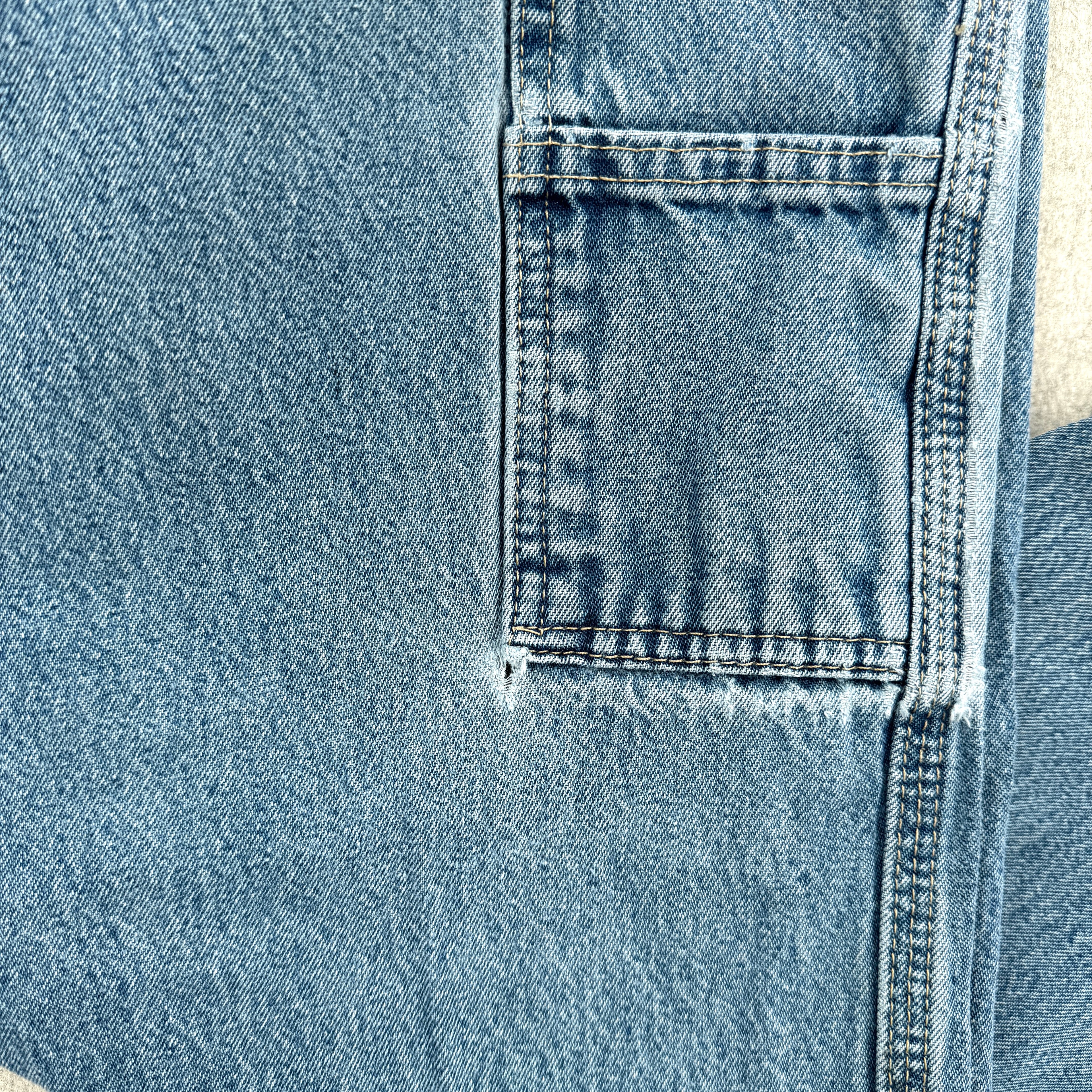Close-up of blue denim fabric with a pocket with a small hole