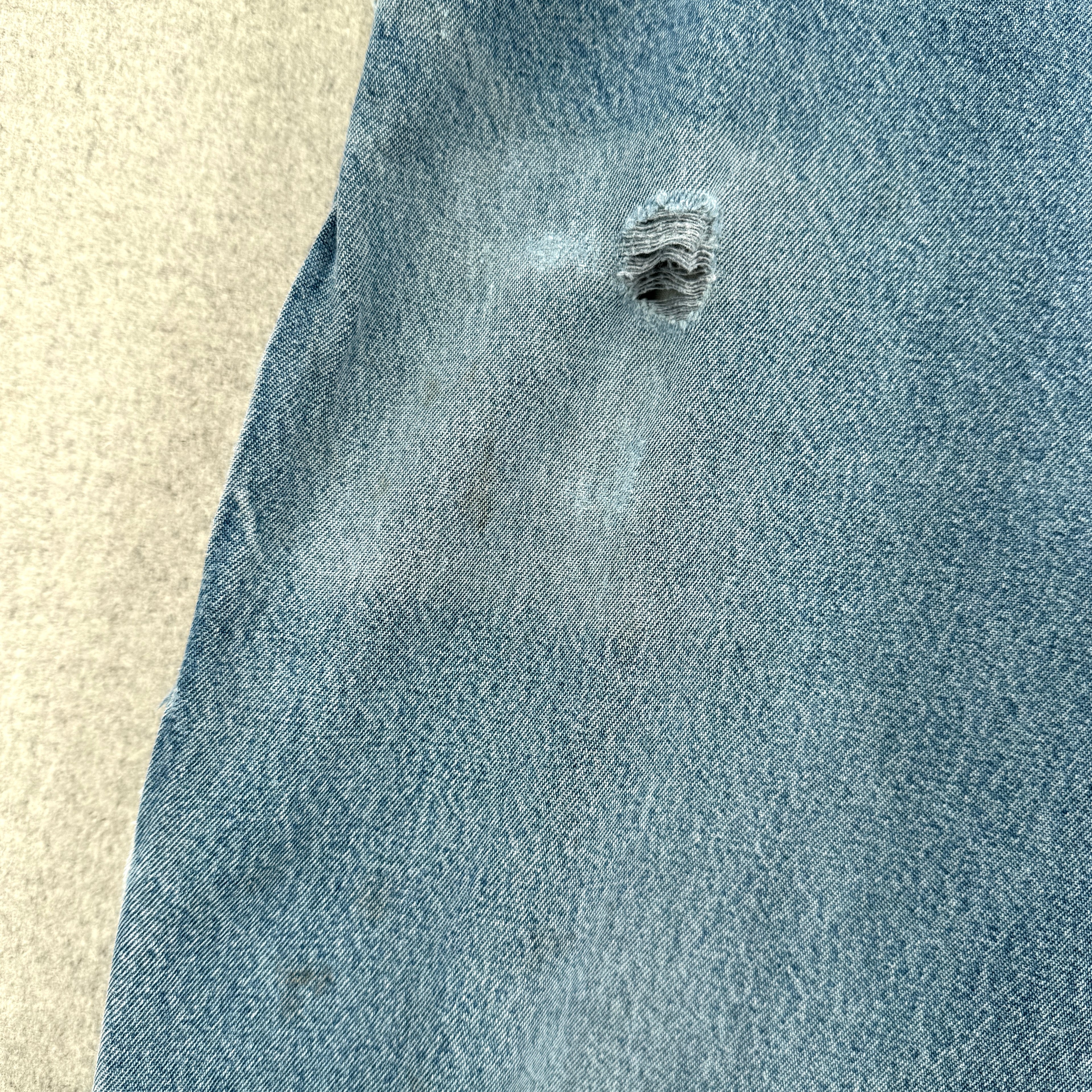 Close-up of a blue denim fabric with a rip on a beige background