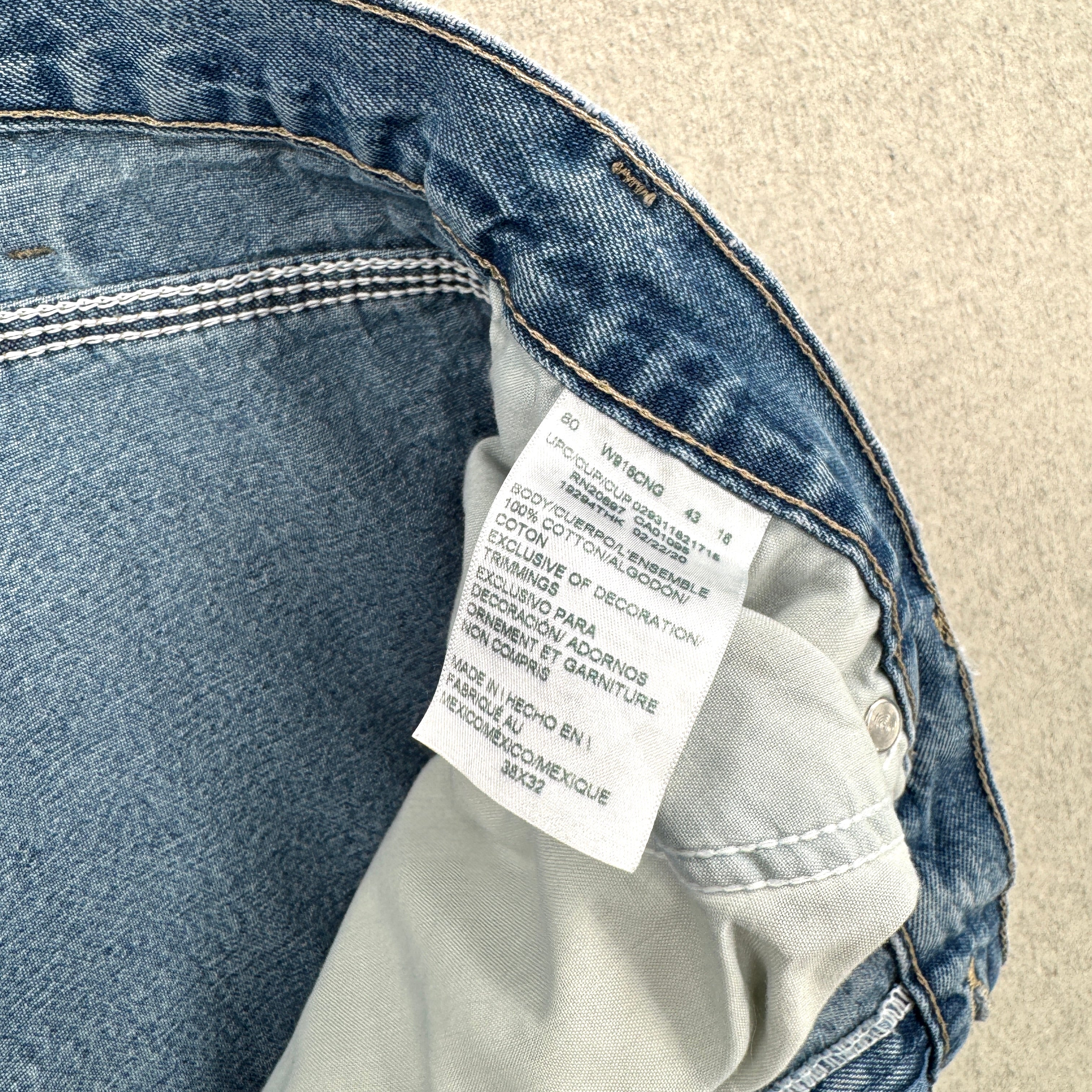 Close-up of a denim jacket with a brand label on a beige background