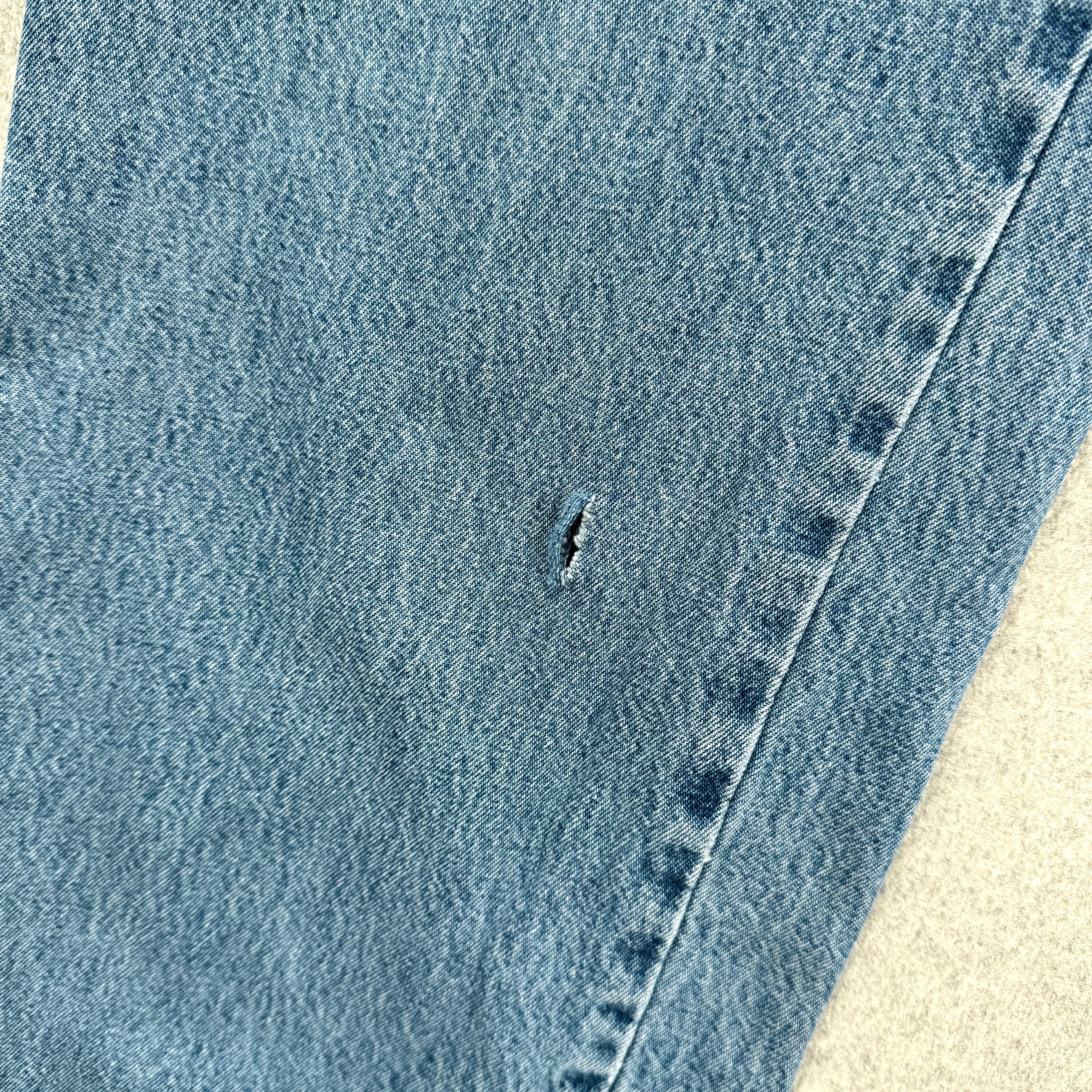 Close-up of a blue denim fabric with a small tear.